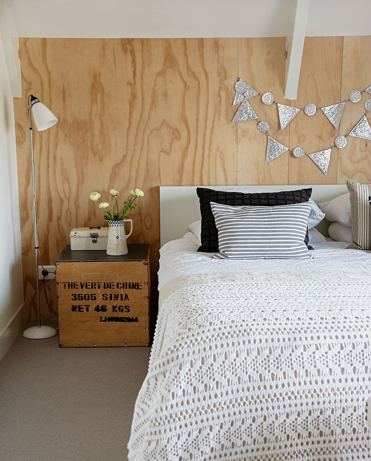 Vloer Briljant Project van Interfloor, bed Ikea, lamp Pols Potten, theekist gevonden op straat in Groningen met ijzeren blad gemaakt door vriend van Rudie, broodtrommel en slinger Bij Lokaal, kan Carlotte Antiek en Brocante, gestreepte kussens zelfgemaakt van vintage katoenen stoffen van grootouders, zwart kussen Kleur op Kleur Interieur, wit beddengoed Livello, sprei Crewel, gehaakte sprei gemaakt door Rudies moeder. vtwonen 04-2021 | productie en styling Ilona Jongepier | fotografie Dana van Leeuwen | tekst Anna van der Heijden