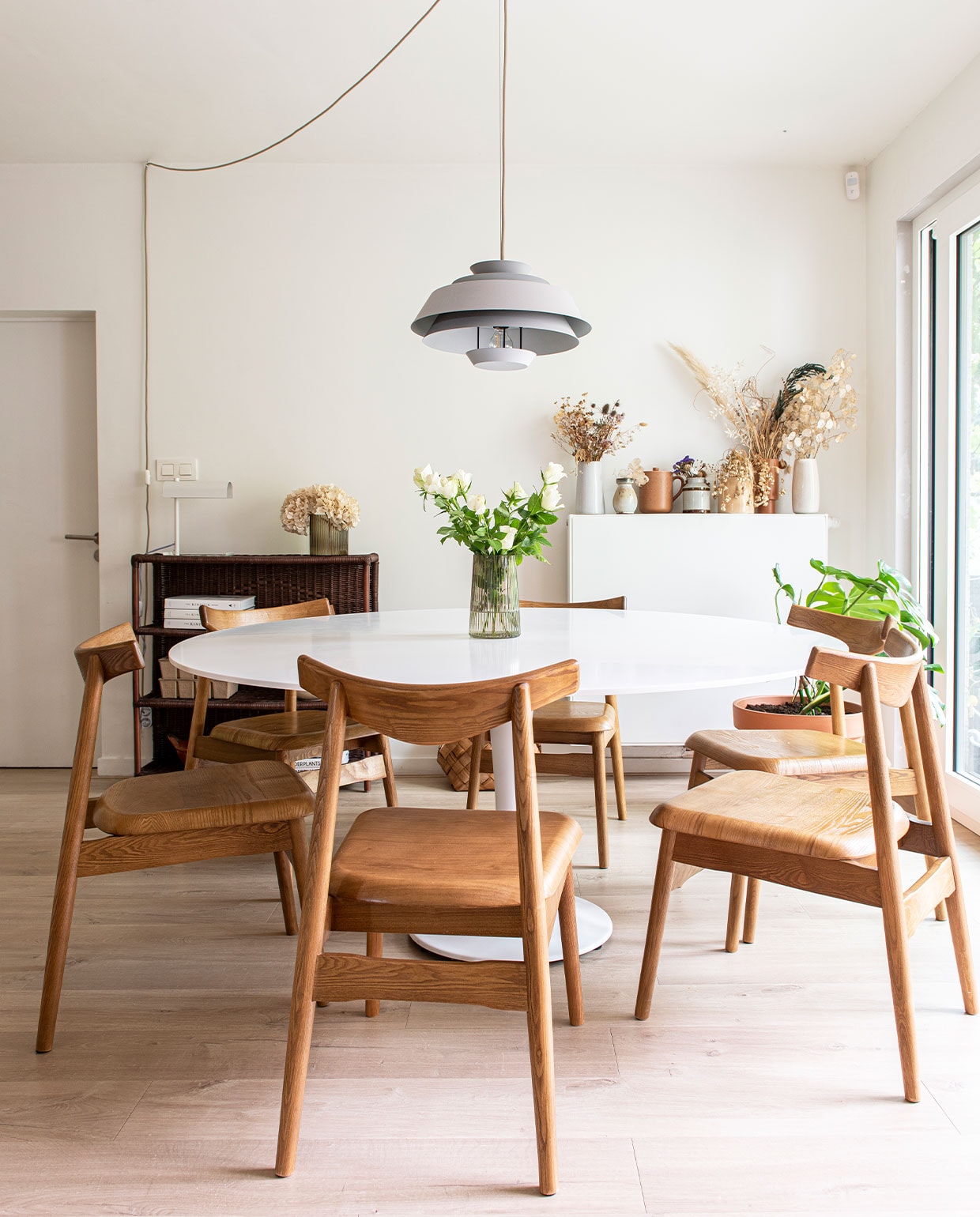 Tafelpoot van La Redoute, corian tafelblad gemaakt door timmerman Wouter Lapage, vaas op tafel Jysk, hanglamp Kwantum. Open rotan kast Merilou. Vazen op verwarming H&amp;M Home, Dille &amp; Kamille en kringloopwinkel. Stoelen, koffiekop en lamp op open kast Zara Home. vtwonen 01-2022 | productie De Binnenkijkers | styling Jeske Weel | fotografie Caroliene Coehorst