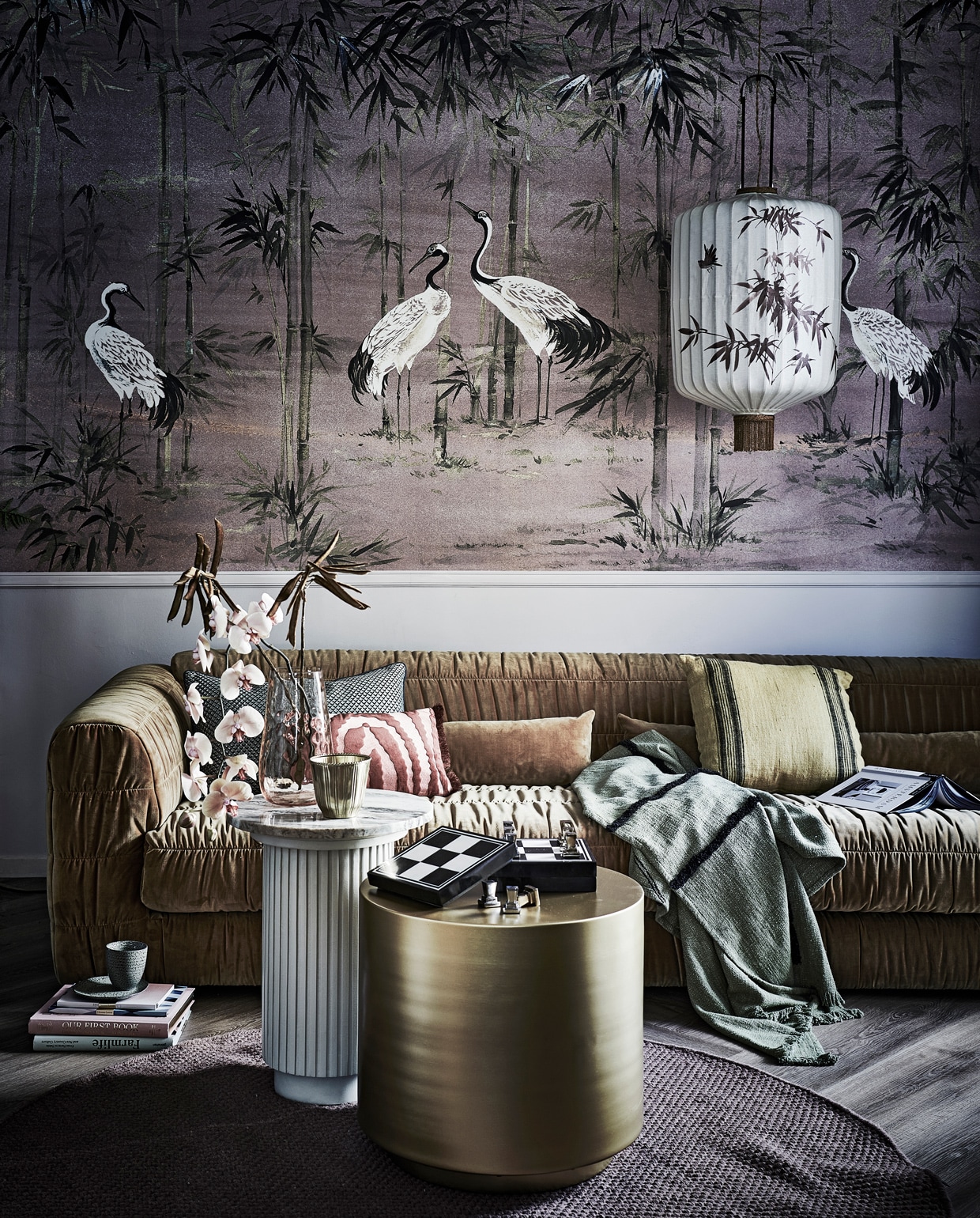 Behang Coordonné Garzas Rose, 400×280 cm (bxh), prijs per paneel € 640,-, groen kussen met print links prijs op aanvraag (luxerybynature.nl). Velours bank Club, gesmokt, inclusief twee kussens 274x108x72 cm (lxbxh) € 2750,-, groene plaid met zwarte streep € 74,95, roze kussen met print € 34,95, groene beker set van 4 € 29,95, groen bord € 9,95, handbeschilderde lamp Lantern XL, 45×92 cm (Øxh) € 595,-, geel kussen met zwarte streep € 29,95 (hkliving.nl). Notitieboekjes per stuk € 15,-, roze boek Our first book € 27,50 (maisonnl.com). Goudkleurige pot € 12,99, boek Farmlife € 39,99, schaakspel per stuk prijs op aanvraag (hm.com). Rond vloerkleed Oksa van Linie Design, 170 cm (Ø) € 221,-, goudkleurige tafel Step van House Doctor 50x50x50 cm € 387,- (vtwonen.nl). Roze, glazen € 95,- (homestede.nl). Bijzettafel Ernie met marmeren blad, 40×54,5 cm (Øxh) € 369,- (nordal.eu). Planten en takken prijs op aanvraag (waterdrinker.nl). vtwonen 13-2021 | styling Liza Wassenaar | fotografie Sjoerd Eickmans | assistentie Kula van den Broek, Demelza Krens, Philine Jansen