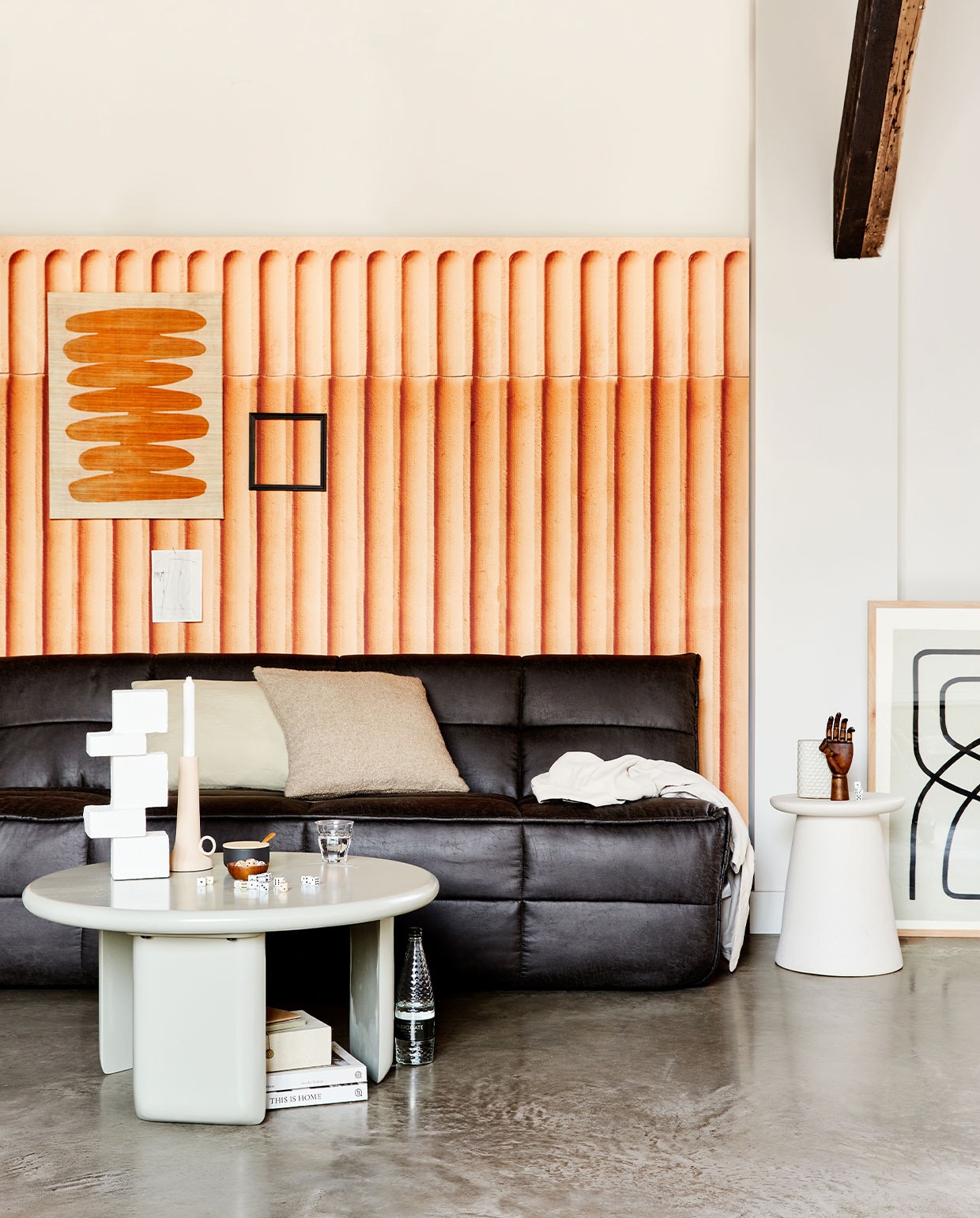 Antracietkleurige 3-zitsbank Cluster, vegan leer, 210x90x80 cm (bxdxh), ook verkrijgbaar in andere stoffen, vanaf € 999,-. Witte keramieken bijzettafel/kruk Button, ook verkrijgbaar in warm groen en taupe, 35×45 cm (Øxh) € 129,-. Bijzettafel Beach, medium 80×41 cm (Øxh) € 399,-, ook verkrijgbaar in small, 64x51x53 cm (lxbxh) € 319,-. | m.m.v. vtwonen.nl (wandkleed Minimalism van Urban Nature Culture, wit object op tafel en kussens van vtwonen, suikerpot van Stelton, artwork rechts van HKliving, kandelaar van Pols Potten), sukha.nl (kaart aan de wand, papieren doosje onder tafel), behangfabriek.com (behang met bogen in terra), sostrenegrene.com (object hand). Overig privébezit. vtwonen 2-2022 | productie Tanja Saarberg | styling Marlies Does | fotografie Bart Brussee | assistentie Neda Farzanyar, Judie Jonker