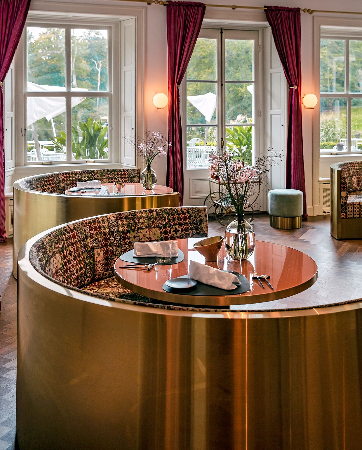 De gebogen messing banken in De Parc-zaal, onderdeel van restaurant Voltaire, zijn op maat gemaakt en geven een gevoel van intimiteit en geborgenheid. Interieurontwerper Judith van Mourik liet ze bekleden met de stof Azulejos van Jean Paul Gaultier voor Lelièvre, de motieven zijn gebaseerd op handbeschilderde azulejos, tegels uit Spanje en Portugal. vtwonen hotels bijlage 13-2020 | Fotografie Ernie Enkelaar  | Tekst Roos Stalpers en Fee van ’t Veen