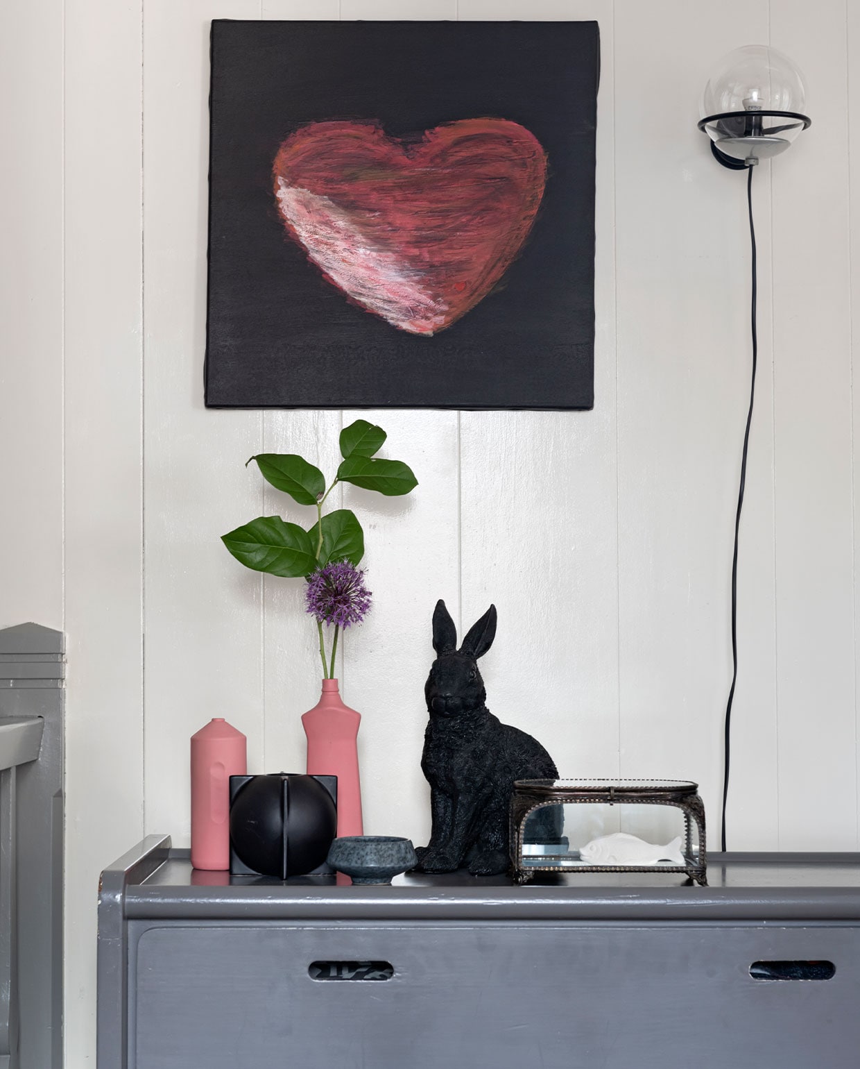 Vintage wandlamp van Gino Sarfatti voor Arteluce, commode uit ouderlijk huis. Roze vazen Foekje Fleur, haas &amp;klevering, schaaltje en vitrinekist Sissy-Boy Homeland. Geluksvis Studio Rode Kers. Schilderij zelfgemaakt. Overig onbekend. vtwonen 13-2021 | styling Sharon Roest | fotografie Caroline Martinot