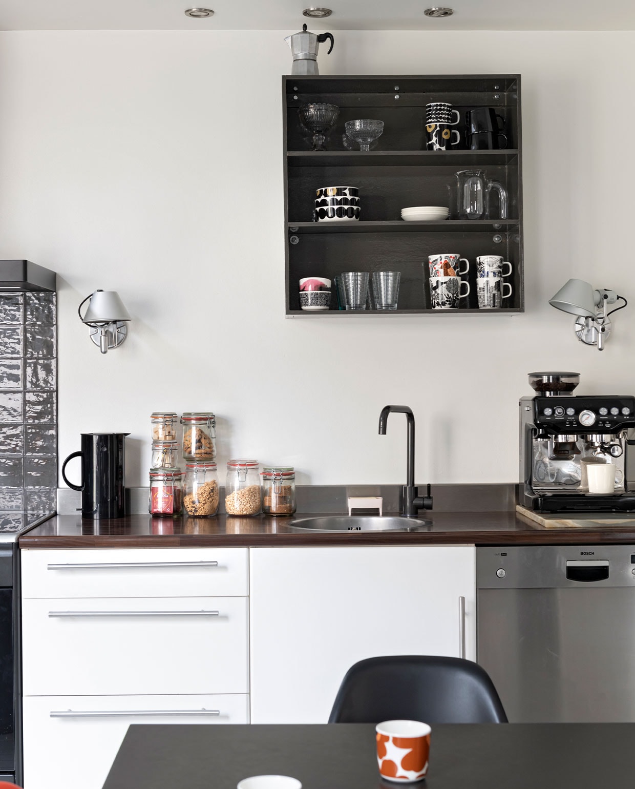 Keuken Ikea, apparatuur Smeg en Bosch. Wandkast gemaakt door Michel. Zellige-tegels Designtegels. Wandlampen Tolomeo van Artemide. Koffieapparaat Barista Express van Sage, waterkoker EM77 van Stelton. Voorraadpotten Dille &amp; Kamille, zeepbakje Bubble Buddy van Foekje Fleur, glaswerk en servies van Iittala en Marimekko via Nio &amp; Elva, sapkan Hay. vtwonen 13-2021 | styling Sharon Roest | fotografie Caroline Martinot