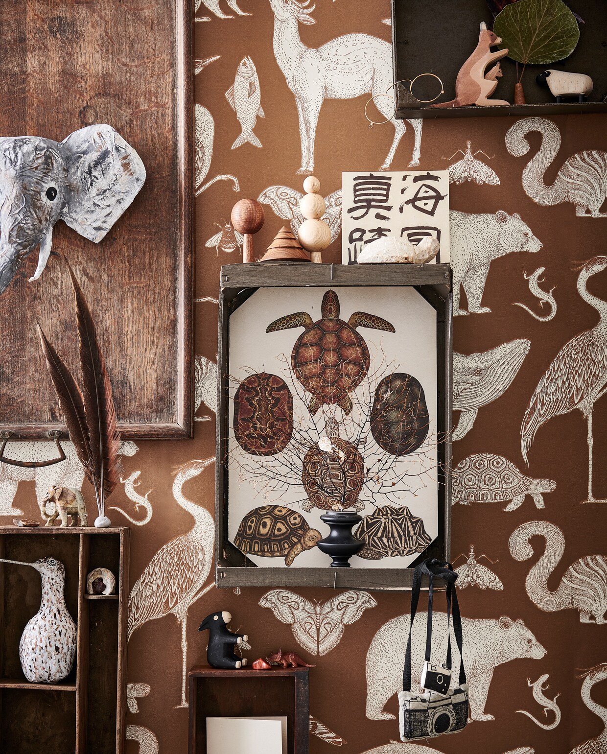 Behang Animals van Katie Scott in kleur Toffee € 99,- (fermliving.com). Oud houten dienblad € 45,-, houten lade € 10,- (burbri.nl). Houten kisten van de groenteboer geschilderd in Peppery Black No. 71 (vestingh.nl). Hand- gemaakte houten bomen € 19,50 (bymolle.com). Papier-maché olifant en grutto gemaakt door Babette Hofstede, prijs op aanvraag (babetteswereld.com). Soapstone Animal Shape schildpad € 5,75, stenen vanaf € 4,25 (iine.nl). Houten kangoeroe € 13,50, houten ezel en schaap, per stuk vanaf € 11,95 (ilovespeelgoed.nl). Zwart koraal € 130,- (allestedlund.com). Beeld olifant kringloop. Overig privébezit. vtwonen 13-2021 kids bijlage | styling Kim van Rossenberg | fotografie Sjoerd Eickman | Assistentie Sanne van der Beek en Judie Jonker\n