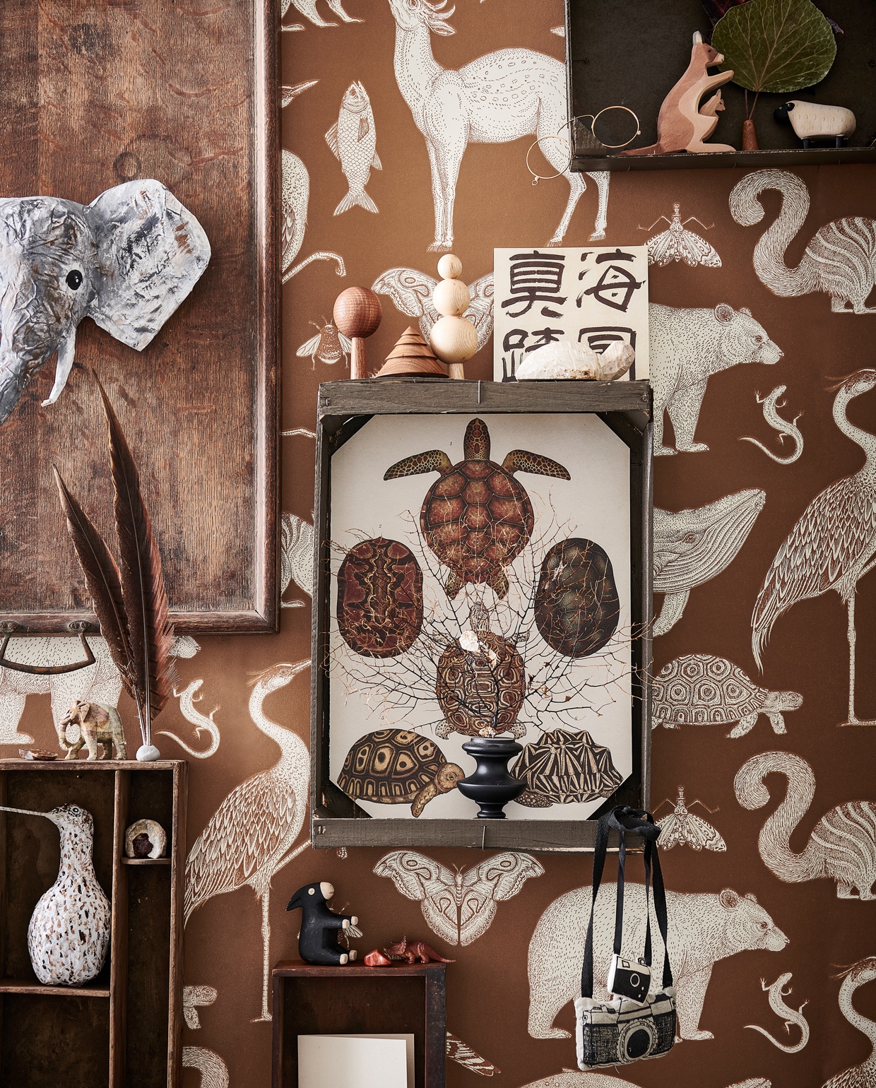 Behang Animals van Katie Scott in kleur Toffee € 99,- (fermliving.com). Oud houten dienblad € 45,-, houten lade € 10,- (burbri.nl). Houten kisten van de groenteboer geschilderd in Peppery Black No. 71 (vestingh.nl). Hand- gemaakte houten bomen € 19,50 (bymolle.com). Papier-maché olifant en grutto gemaakt door Babette Hofstede, prijs op aanvraag (babetteswereld.com). Soapstone Animal Shape schildpad € 5,75, stenen vanaf € 4,25 (iine.nl). Houten kangoeroe € 13,50, houten ezel en schaap, per stuk vanaf € 11,95 (ilovespeelgoed.nl). Zwart koraal € 130,- (allestedlund.com). Beeld olifant kringloop. Overig privébezit. vtwonen 13-2021 kids bijlage | styling Kim van Rossenberg | fotografie Sjoerd Eickman | Assistentie Sanne van der Beek en Judie Jonker\n
