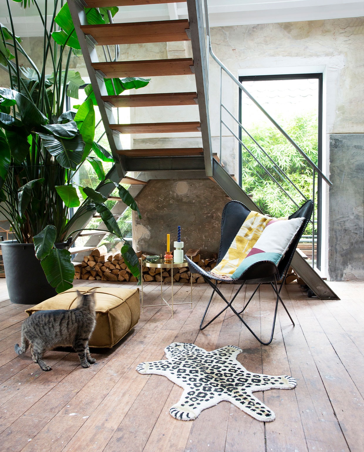Zwarte vlinderstoel vintage. Plaid en kussen HKliving. Poef Fonq. Kleed Doing Goods via Sissy-Boy Homeland. Bijzettafel Zuiver. Kandelaren en plant onbekend. vtwonen 13-2021 | productie De Rookerij | styling, fotografie en tekst Jeltje Janmaat | tekstbewerking Anne van den Dool