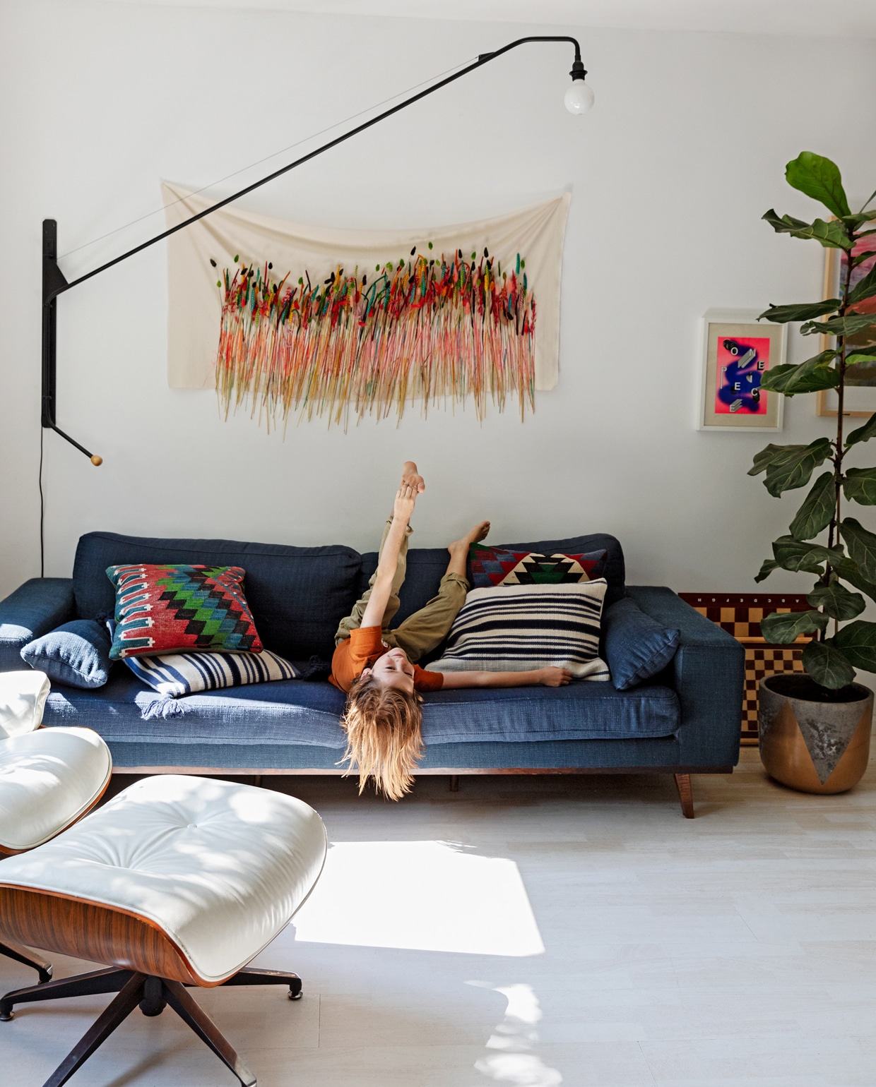 Bank Wehkamp. Kussens Ikea en Arket. Wandlamp Potence van Vitra. De witte lounge chair met Ottoman is een kopie van Eames. Wanddoek met geverfde grassen eigen werk. Pot goud/grijs Van Pot Los. Zeefdruk Tim Wilders/Atelier Haven. Schaakbord meegenomen uit Londen. vtwonen 13-2021 | styling Ilona Jongepier | fotografie Dana van Leeuwen