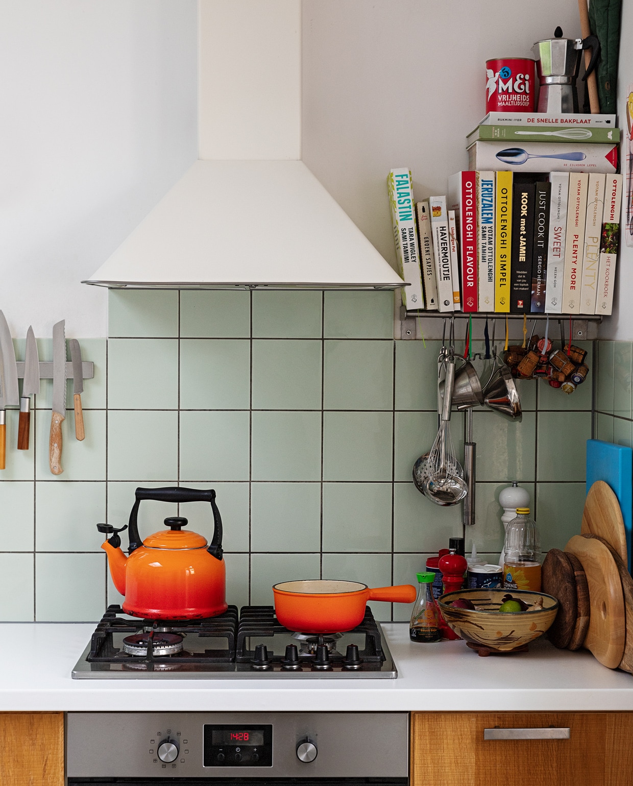 Oranje fluitketel en pan Le Creuset. Messen Suncraft, Opinel en Dille &amp; Kamille. Kookboeken Ottolenghi, Jamie Oliver, Sergio Herman, Yvestown in de keuken, De Zilveren Lepel. Snijplanken Hay, Ikea en Serax. Peper- en zoutmolen Peugeot. Soeplepel Brabantia. Hangend rvs keukengerei Dille &amp; Kamille. Percolator tweedehands. Schaaltje van een pottenbakkersmarkt. Afzuigkap en oven Ikea. Ovenhandschoen Kook. Pollepel Kookhuis aan de Maes. vtwonen 13-2021 | styling Ilona Jongepier | fotografie Dana van Leeuwen