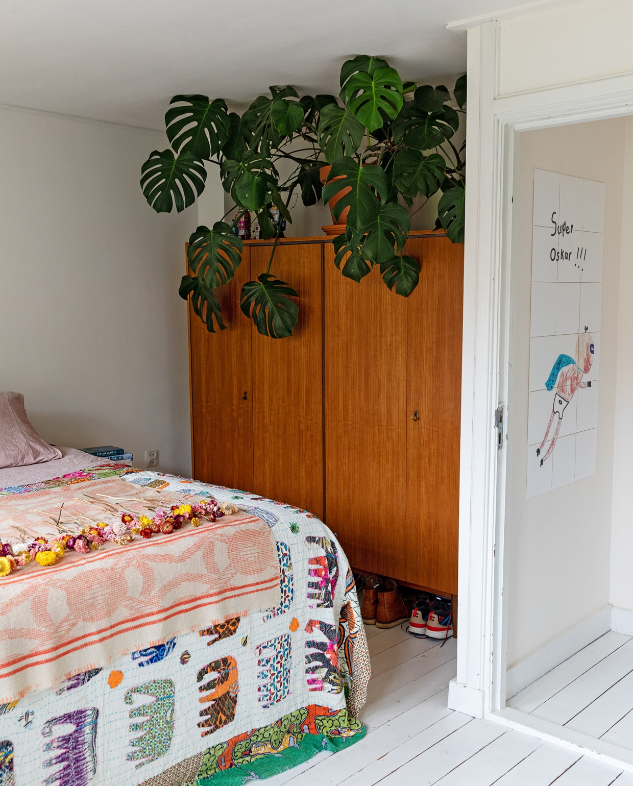 Bruine kast Marktplaats. Deken met olifanten souvenir uit India. Roze plaid met gedroogde bloemen Loesje van Herp. Tekening in de gang gemaakt door Oskar. Gatenplant Monstera Sissy-Boy. vtwonen 13-2021 | styling Ilona Jongepier | fotografie Dana van Leeuwen