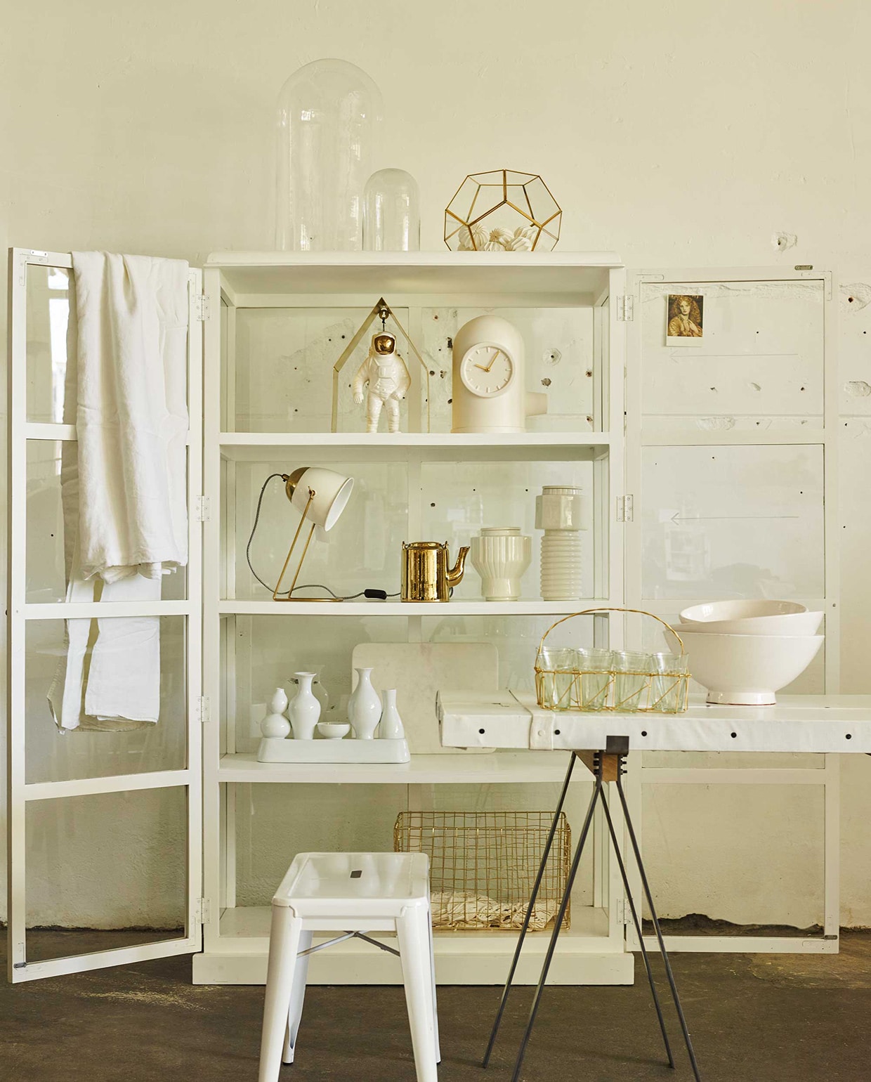 Vitrinekast, kruk, glazen stolpen (Portrait). Glazen windlicht facet met goudkleurige randen, papieren bollenslinger (Nordal). Schragen (Van Mokum). Tafelblad (Combitex). Op tafel: schalen (Household Hardware). Draadmandje met glazen van Madam Stoltz (Deens). In de kast: gouden huisje, vazen met ribbels van Diesel (Nijhof). Astronaut, klokvaas (Van Mokum). Lamp van Madam Stoltz, marmeren snijplank van Madam Stoltz (Deens). Theepot, vazen-vaas (Pols Potten). Draadstalen mand (Portrait), linnen kleed, gehaakt hesje (H&amp;M). vtwonen 07-2016 | fotografie Tjitske van leeuwen | styling Marianne Luning