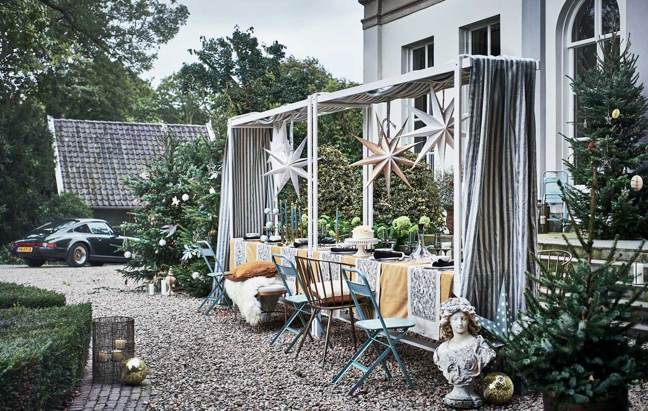 ^ Tafels met bovenstel, p.o.a. (com-anders.nl). Kerstbomen (janvanvulpenboom­kwekerij.nl). Handgemaakte gerecyclede kerstballen vanaf € 6,95, piek € 12,50, klapstoelen, per stuk € 65,- (weldaad.com). Blauw blad met zilverkleurig accent in kerstboom, per stuk € 18,49 (silk-ka.nl). Kerstverlichting € 22,99 (tcdebosrand.nl). Papieren ei, maat XL € 12,-, geel kussen, 50×50 cm € 45,-, papieren kerstboom, 24 cm (h) € 11,-, papieren sterren vanaf € 34,- (bungalow.dk). Discoballen, per stuk € 32,50 (spektakelwonen.nl). Stompkaarsen vanaf € 4,99, tafellakens, 140×240 cm per stuk € 14,99, tafelloper vanaf € 9,99, servet, set van 2 € 9,99, cocktailglazen, per stuk vanaf € 7,99, fles met zwarte stop € 19,99, vierkante kandelaars vanaf € 17,99, dinerkaarsen, set van twee € 1,99, bankje € 199,- (hm.com). Blauwe chocolade kerstballen, per stuk € 7,95 (toutpatisserie.nl). Goudkleurige eetkamerstoel van Clayre &amp; Eef, 51x55x79 cm € 260,99, schapenvacht Sheepskin van Weltevree € 79,-, vierdelige serviesset Vera Wang Jardin van Wedgwood € 119,-, bestek Mademoiselle van Villeroy &amp; Boch, 68-delig € 379,-, messing dienblad van Oyoy Living Design € 60,-(vtwonen.nl). Taart Pierrot € 34,95 (huizevanwely.nl). Goudkleurig plateau met drie lagen € 138,- (nhflowers.nl). Lantaarn links € 127,50 en rechts € 75,- (allestedlund.com). Kandelaars, per stuk € 65,- (wildschut-antiques.com). Buste € 325,- (harlequin-lisse.biz). Goudkleurig kussen, per stuk € 39,95 (nordal.eu). Gestreepte doek Endless Summer Stripe van Barbara Osório, 310 cm (l) € 139,- (wva.nl). vtwonen 12-2021 | styling Liza Wassenaar | fotografie Sjoerd Eickmans