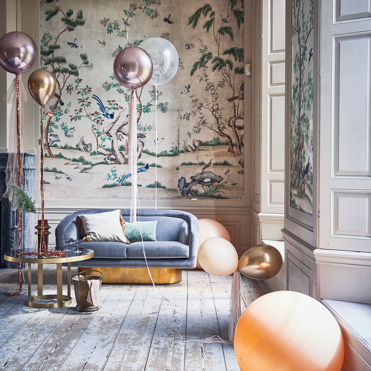 Ballonnen (partyballoon.nl). Tule (boerenbonthal.nl). Franjegordijn (slinger.nl). Glazen salontafel 45×80 cm, vaas, fluwelen kussen met franjes (nordal.eu). Groen kussen, grijze champagneglazen metribbel van Ferm Living(vtwonen.nl). Zilvergrijze fluwelen bank van Jonathan Adler (ankevangoor.com). Champagnekoeler (iblaursen.dk).