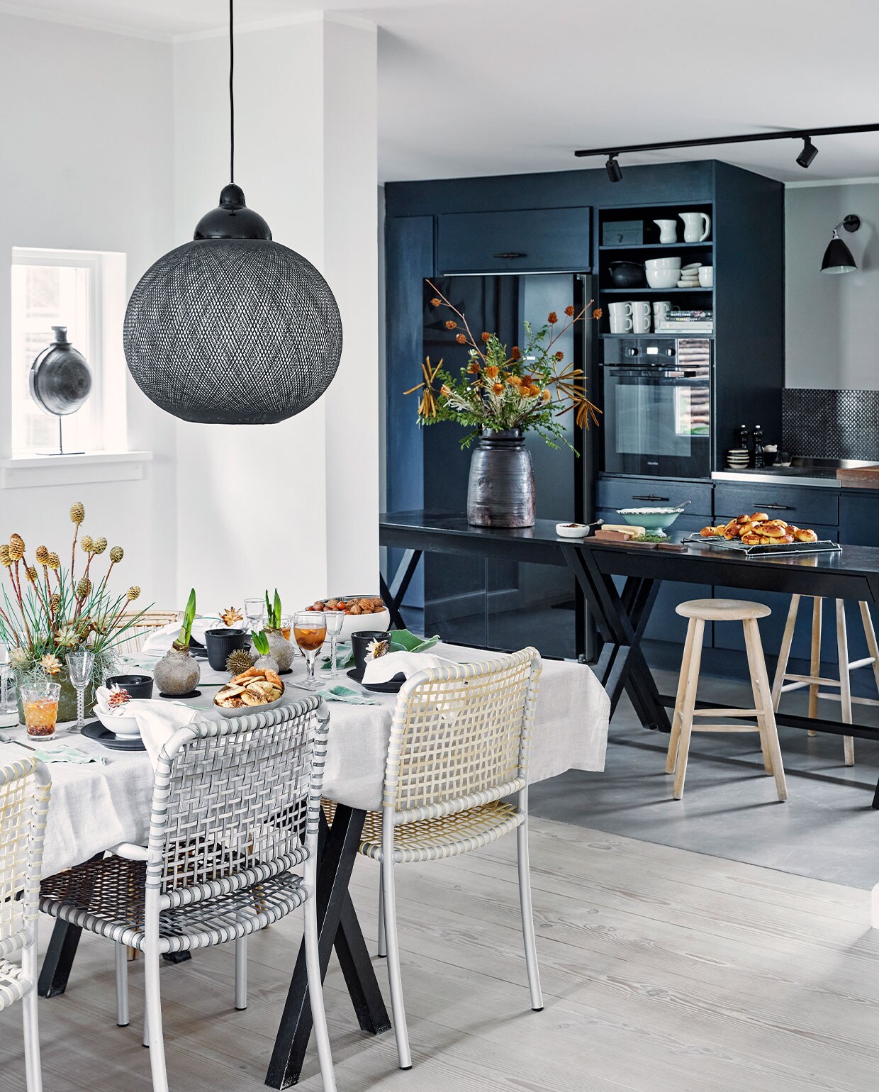 Oude Boform keuken en Ilva tafels geschilderd in Railings van Farrow &amp; Ball. Handvaten kastjes Brandt Collective, tegels Made a Mano. Houten krukken Louisiana Design Butik. Zwarte vaaspot The Travelling Band. Eettafel zelfgemaakt door Henrietta. Stoelen Allu van Paola Navone voor Gervasoni. Hanglamp Non Random Light van Moooi. Tafelkleed en servetten Georg Jensen Damask. Zwart servies Royal Copenhagen. Overig herkomst onbekend. vtwonen 12-2021 | Productie Living Inside | Fotografie Martin Sølyst | Tekst Eva-Marie Wilken | Tekstbewerking Caroline Westdijk
