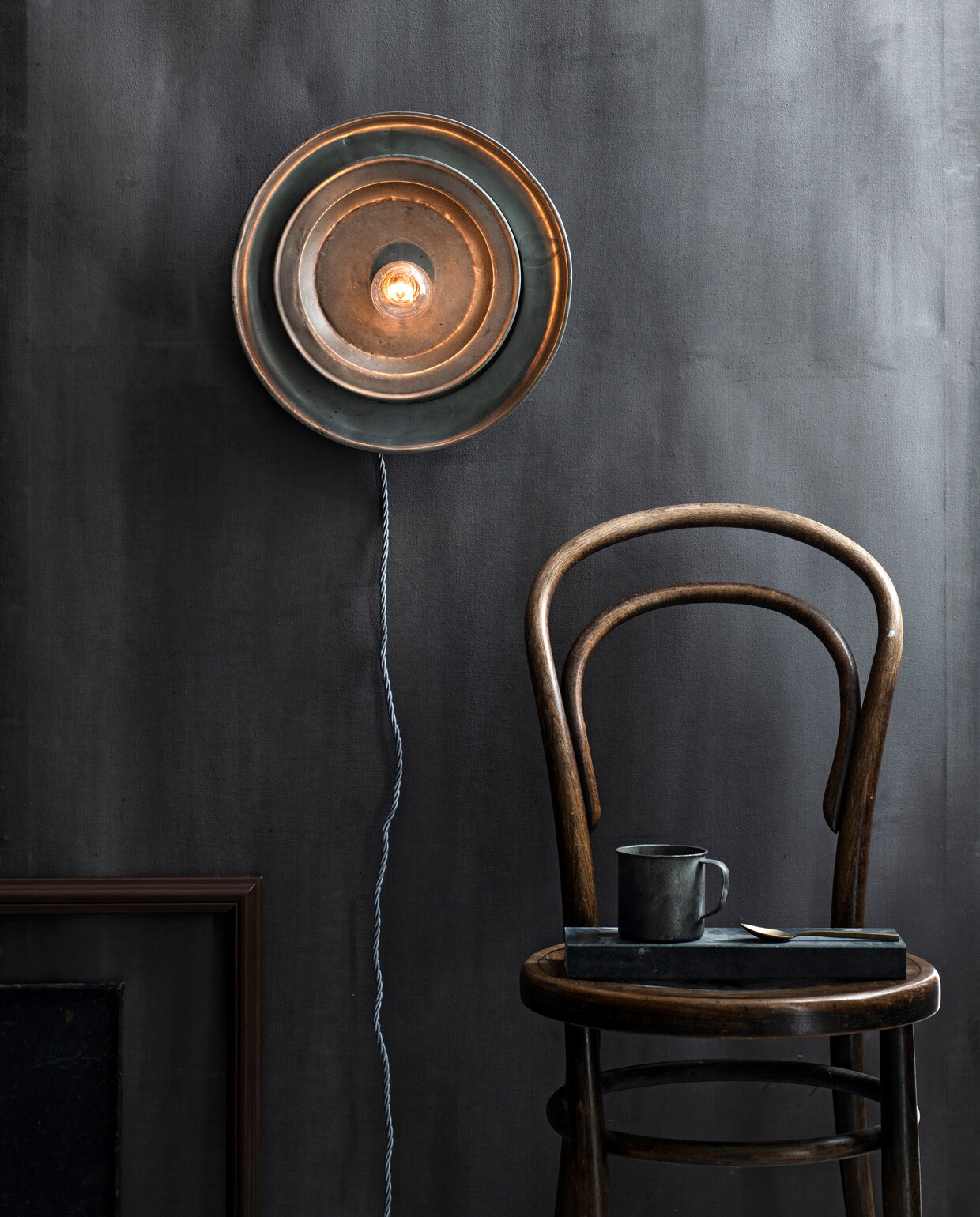 Op de wand kalkverf in kleur Black Smoke van Fresco (pure-original.nl). Thonet stoel, oude fotolijst (com-anders.nl). Tinnen borden en mok (jolandelijk.nl). Overig privébezit. vtwonen 13-2021 | productie &amp; styling Marlies Does | fotografie Louis Lemaire