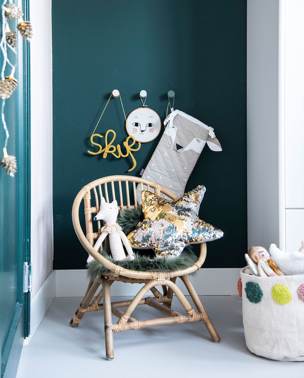 Stoel, groene placemat Casa. Ster-kussen H&amp;M Home. Pop Afkes. Opbergtas Hema. Guirlande van dennenappels Jysk. Wandhaken Kukeluusje. ‘Skye’ (naam geschreven met draad) jibbejebba.nl. Vloer Novilon. Overig herkomst onbekend. vtwonen 12-2021 | productie Insidehomepage | styling Laura Gommans | fotografie Louis Lemaire
