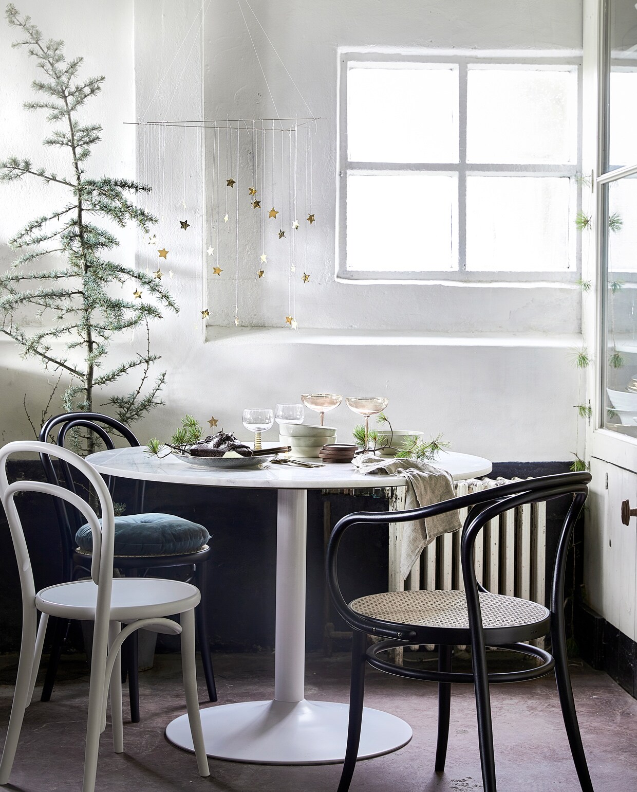Eettafel Cadiz van Vestbjerg € 425,- (vtwonen.nl). Stoel met armleuning en webbing zitting € 289,95, zwarte stoel zonder armleuning € 199,95, witte stoel € 149,95, linnen servet € 6,95 (dille-kamille.nl). Glazen met groene voet, per stuk € 9,95 (hkliving.nl). Roze glazen van Nordal, per stuk € 12,-, groen bord van Madam Stoltz € 10,- (deens.nl). Blauwe ceder 30×175 cm (dxh) € 59,99 (intratuin.nl). vtwonen 12-2021 | styling Marlies Does | fotografie Peggy Janssen