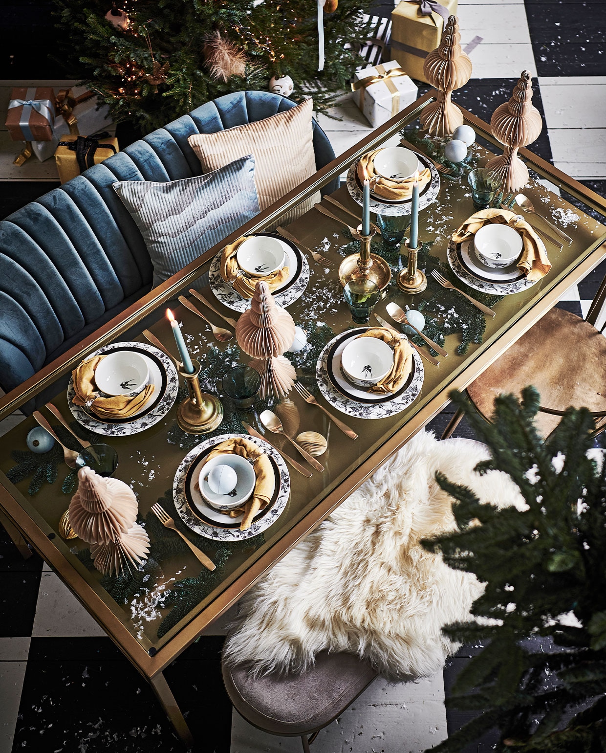 Bloemstyling, p.o.a. (judithslagter.nl). Papieren kerstbomen 24 cm (h), per stuk € 12,-, papieren ei maat XL, per stuk € 12,-, servet, set van twee € 12,-, glazen, per twee € 23,50 (bungalow.dk). Inpakpapier € 3,99, grijze bank € 199,-, groot bord met print, per stuk € 9,99, wit bord met zwarte bies, per stuk € 7,99, kom, per stuk € 7,99, dinerkaarsen, per twee € 1,99 (hm.com). Chocolade kerstballen, per stuk € 7,95, (toutpatisserie.nl). Bestek, per stuk € 6,99, servetring, set van 4 € 17,99 (zarahome.com). Kunstsneeuw, p.o.a., kerstverlichting € 22,99 (tcdebos-rand.nl). Schapenvacht Sheepskin van Weltevree € 79,-, goudkleurige eetkamerstoel van Clayre & Eef 51x55x79 cm € 260,99, blauwe bank van Moos Indy € 389,- (vtwonen.nl). Kandelaars, per stuk € 65,- (wildschut-antiques.com). Beige pluimen in boom, per stuk € 3,20 (sostrenegrene.com). Handgemaakte gerecyclede kerstballen vanaf € 6,95 (weldaad.com). Tafel € 1339,-, kussens, per stuk € 39,95 (nordal.eu). Lint privébezit. Kersttakken (waterdrinker.nl). vtwonen 12-2021 | styling Liza Wassenaar | fotografie Sjoerd Eickmans | assistentie Kula van den Broek, Sanne Ketelaar | bloemstyling Judith Slagter