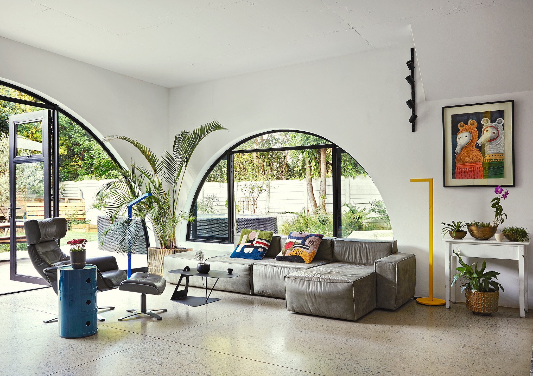 Grote woonkamer van Gina en Asher met grijze hoekbank, grote ramen en diverse kunst Beeld: productie LIVING INSIDE/BUREAUX | fotografie Elsa Young | tekst GRAHAM WOOD | tekstbewerking  Cathelijne van Wingerden