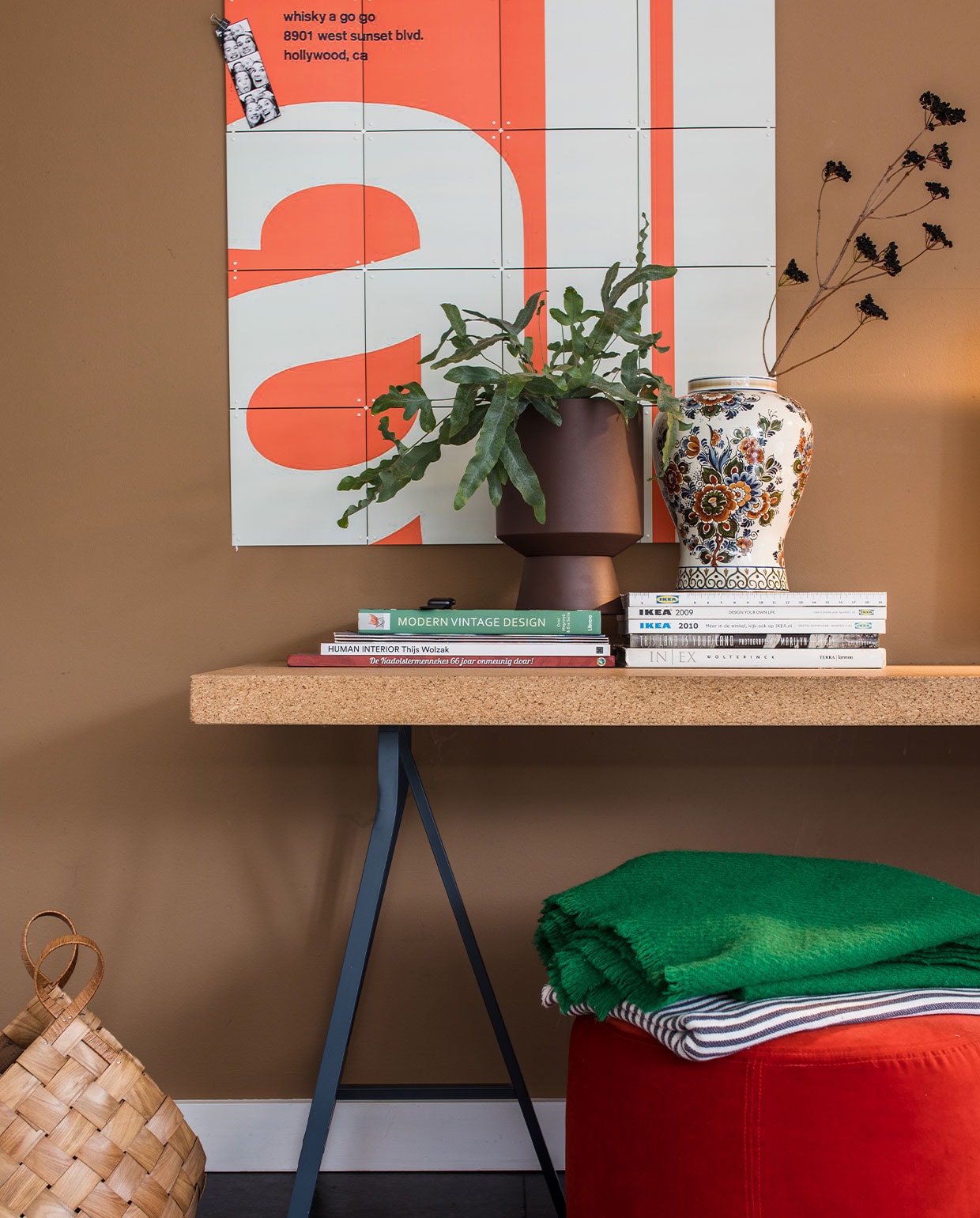 Scratch Acid &amp; All With Chemical People Punk Rock Concert geprint op Ixxi Your World. Bureau met blad van kurk Sinnerlig-collectie Ikea. Bloempot rechts Jysk. Plant tuincentrum. Kaststel gekregen van Maaikes oma. Beeldscherm Apple. Plastic bureaustoel Vitra PACC van Charles &amp; Ray Eames, Flinders. Poef Ikea Stockholm. Gestreepte plaid Ikea. Groene wollen plaid Hay. Mand Thuuz. Vacht Koldby, Ikea. vtwonen 10-2021 | Productie en Fotografie Corine Hoge Bavel | Tekst Marion de Boer