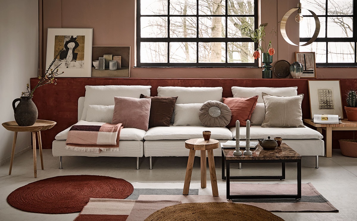 Wand geschilderd in Skin Powder, lambrisering in Cardinal Red, matte krijtverf (Pure &amp; Original). Bank Soderhamn, tafel Stockholm (Ikea). Op de bank kussens v.l.n.r. roze (Trendhopper), bruin (Ikea), rond (Loods 5), gewassen linnen in de kleur roze en écru, plaid, wollen vloerkleden met blokpatroon (H&amp;M Home). Ronde juten vloerkleden, 3-poot kruk, bijzettafel van gerecycled hout (Kwantum). Salontafel marmerlook, goudkleurige metalen hanglamp Yane, op lambrisering hoge glazen vaas Bali, tweekleurige vaas, mand onder sidetable (Trendhopper). Decoratiebord (Kwantum). Cementen vintage kruik, goudkleurige Japanse theepot, kommetjes, kaarsen (Loods 5). Alle kunst komt van de SBK Kunstuitleen Amsterdam. vtwonen 05-2018 | Fotografie Alexander van Berge | Styling Fietje Bruijn