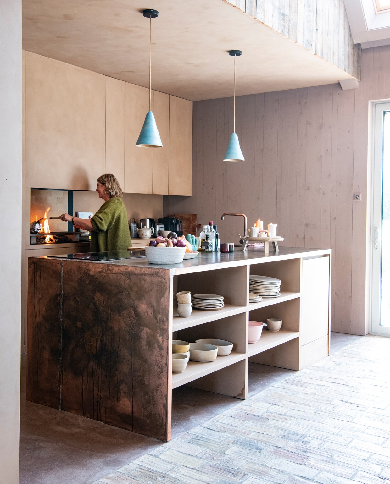 Keuken en kookeiland ontworpen door Larissa. Werkblad en kraan Hotbath. Kookplaat Inventum. Lampenkappen keramist Loeke Pam. Servies eigen ontwerp, in samenwerking met Loeke Pam. Achter grill chamotte haard­tegels Van Scheppingen. Op de vloer oude Franse tegels via Jan van IJken Oude Bouwmaterialen. Tableau voor kaarsen Ikea. Op de kasten kalkverf Topaze van Pure &amp; Original, op de wand Rose Dust van Pure &amp; Original, via Piccolina Schilderwerken. Overig herkomst onbekend. vtwonen 11-2021 | styling Esther Jostmeijer | productie Insidehomepage | fotografie Louis Lemaire tekst Inge van Lieshout | tekstbewerking Sunna Borghuis