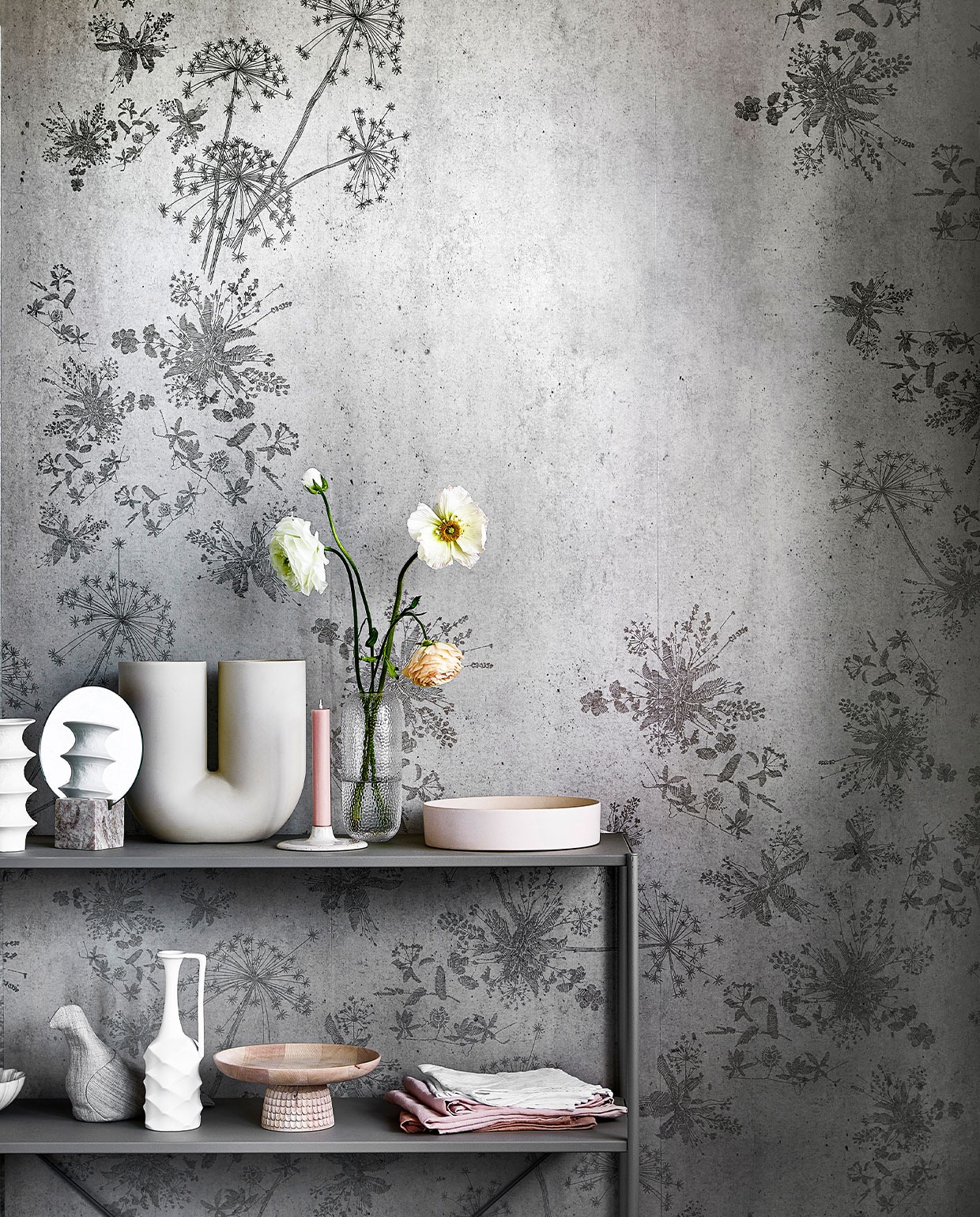 Digitaal behang Wild Flower Concrete, 6 banen van 280×50 cm, totaal (lxb) 280×300 cm. M.m.v. loods5.nl (stellingkast), loods5.nl/design (witte vazen uit set van vier, roze schaal), hm.com (spiegel in marmeren blok), kasstoor.nl (U-vormige vaas, houten etagère), letoile.store (kandelaar, roze theedoeken), bolia.com (glazen vaas, gebroken-witte schaal), homestede.nl (stoffen vogel), paviljoennoord.com (schalen met geschulpte rand, witte theedoeken), hm.com (glazen gieter). Overig privébezit. vtwonen 05-2021 | productie Tanja Saarberg | styling Danielle Verheul | fotografie Peggy Janssen | assistentie Niels Kist, Danique van Rijn