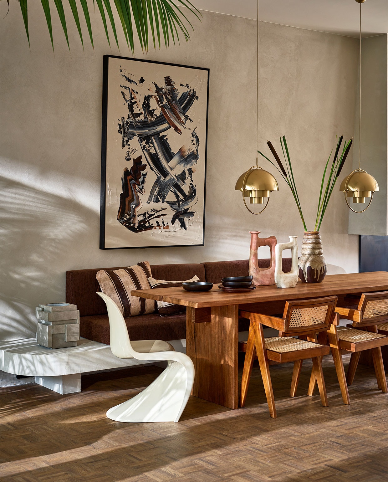Op maat gemaakte tafel van frakéhout, prijs op aanvraag (@takumi_interior). Abstract schilderij van Patrick van Riemsdijk (patrickvanriemsdijk.com). Tamegroute vaas, klein € 115,-, groot € 138,- (householdhardware.nl). Houten armstoelen Detjer Office Chair, € 425,- (casagitane.com). Hanglampen Multi Lite Pendant Large Brass van Gubi, € 839,- (nordicnew.nl). Vintage jaren 70- vaas € 50,- (vandijkenko.nl). Witte kunststof stoel Panton Chair van Verner Panton uit 1974, € 750,- (neeflouis.nl). Donkerbruine keramische borden Home Chef, diep € 16,95, plat € 17,95 (hkliving.nl). Betonnen wijnkoeler € 149,- (serax.com). Bruin/beige gestreept kussen, 50x60 cm € 149,-, bruin/beige gestreept kussen, 60x40 cm € 149,- (couleurlocale.eu). vtwonen 09-2021 | styling Cleo Scheulderman | fotografie Jeroen van der Spek | assistentie Krystel Jane Robinson
