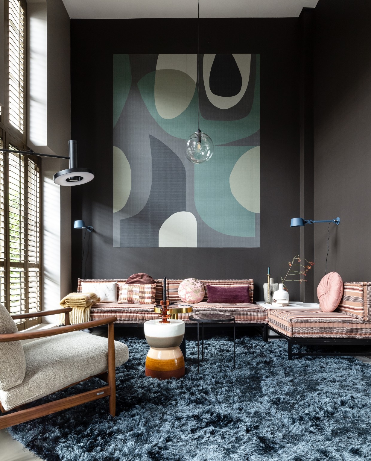 Lange wand met shutters in kleur Boomschorsbruin, donkere hoek waar bank staat in kleur Fading Horizon, Flexa. Op maat gemaakte shutters in de kleur rustic grey, JASNO shutters. Op de wand behang mural Artifact – 312483, Eijffinger. Elementenhoekbank, kussens, Householdhardware. Fauteuil Todd van Pols Potten via Eijerkamp. Vloerkleed Arezzo op maat gemaakt, Eijerkamp. Blauwe bijzettafel Glam, zwarte bijzettafel Glazed, Zuiver. Keramische kruk Glazed, vtwonen. vtwonen weer verliefd op je huis seizoen 15, aflevering 9 | styling Fietje Bruijn | fotografie Sonja Velda