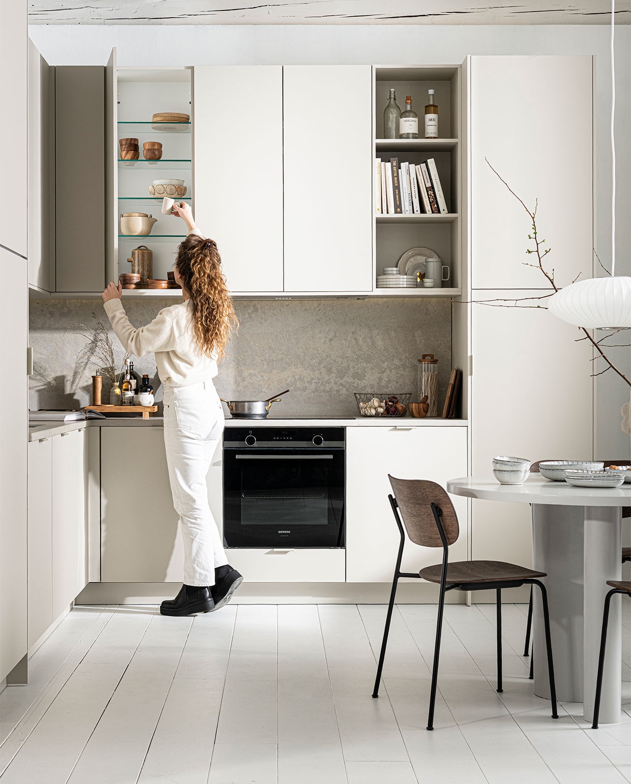 Keuken Basic Greige, zoals getoond, exclusief accessoires € 22.500,- | M.m.v. sjostrandcoffee.nl (koffiezet­apparaat en melkopschuimer), menuspace.com (eetkamerstoel Co), com-anders.nl (eettafel), sissy-boy.com (vaas), vtwonen.nl (servies op tafel van Serax, keukenrek van Ferm Living), thefinestore.com (dienblad en kopje). Overig privébezit. vtwonen 12-2021 | productie Tanja Saarberg | styling Kim van Rossenberg | fotografie Sjoerd Eickmans