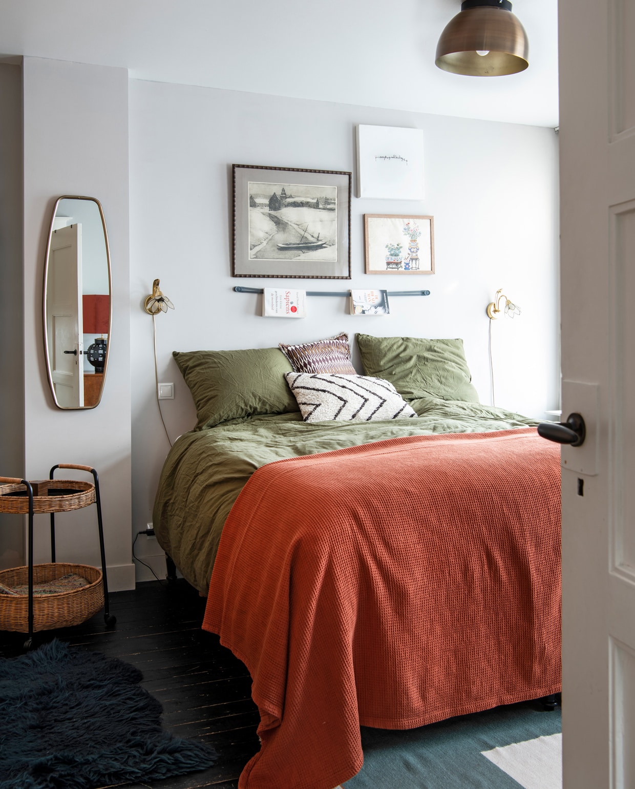 Bijzettafel Ikea. Spiegel Xenos. Nachtlampen kringloop. Kunst aan de muur familiestukken, kringloop en souvenir. Leren boekenriem aan muur Droog Design. Dekbedovertrek H&amp;M. Plaid Kwantum. Wit kussen HKliving, bruin kussen Madam Stoltz. Plafondlamp Karwei. Vloerkleed Sissy-Boy. vtwonen 10-2021 | Productie Insidehomepage | Fotografie Louis Lemaire | Styling en tekst Inge van Lieshout | Tekstbewerking Renate Dahlmans