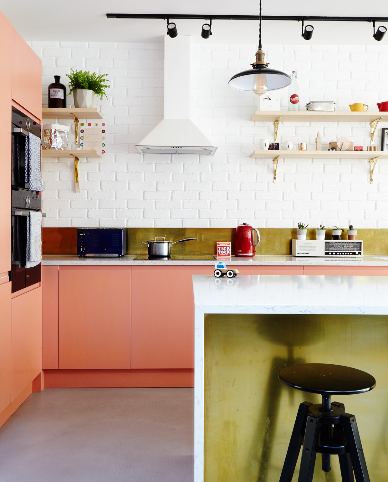Het perzikkleurige roze van de keukenkasten is ‘afgekeken’ van een Acne draagtas. De geverfde frontjes werden op Ikea onderkastjes geplaatst. De koperen spatwand is een verrassende combinatie met de wit geschilderde baksteenstrips. vtwonen 1-2020 | Productie features &amp; more | Fotografie Penny Wincer | Tekst Jo Leevers \n\nvtwonen 1-2020 | binnenkijken in een rijtjeshuis in Londen woonkeuken kleurrijk