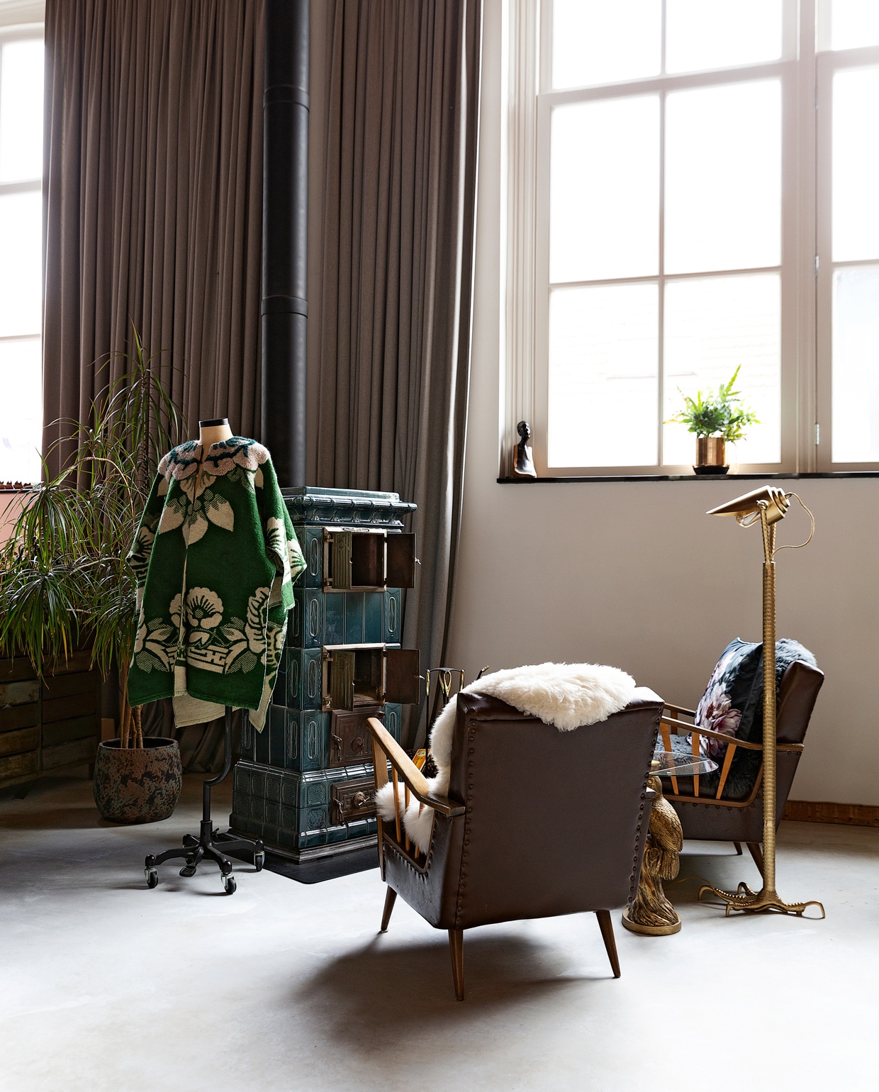 Antieke tegelkachel Harrie van Gennip. De fauteuils zijn erfstukken. Jas eigen ontwerp voor Studio Wunderbar. Vloerlamp Falcon Dutchbone. Gordijnen zelfgemaakt. vtwonen 10-2021 | styling Emmy van Dantzig | fotografie Jansje Klazinga