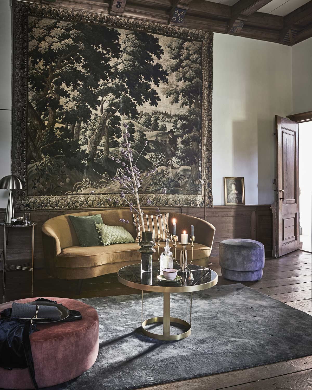 Okergele sofa London (Sissy-Boy). Salontafel, vaas, vierarmige kandelaar, kandelaar voor stompkaars, glas (Nordal). Vloerkleed en poefs (4x6sofa). Hoge bijzettafel met marmeren blad van Gubi (Goeds). Groene kussenhoes, zijden kussenhoes met balletjes, gestreepte kussenhoes (H&amp;M). Glazen karaf soortgelijk prijs op aanvraag (Prinsheerlijk Antiek). Goudkleurige lamp (Hübsch Interior). Roze kom, groen bordje (Anouk Kramer). Notitieboek (Madam Stoltz). Overig privébezit. vtwonen feestspecial 12-2018 | Fotografie Jeroen van der Spek | Styling Cleo Scheulderman