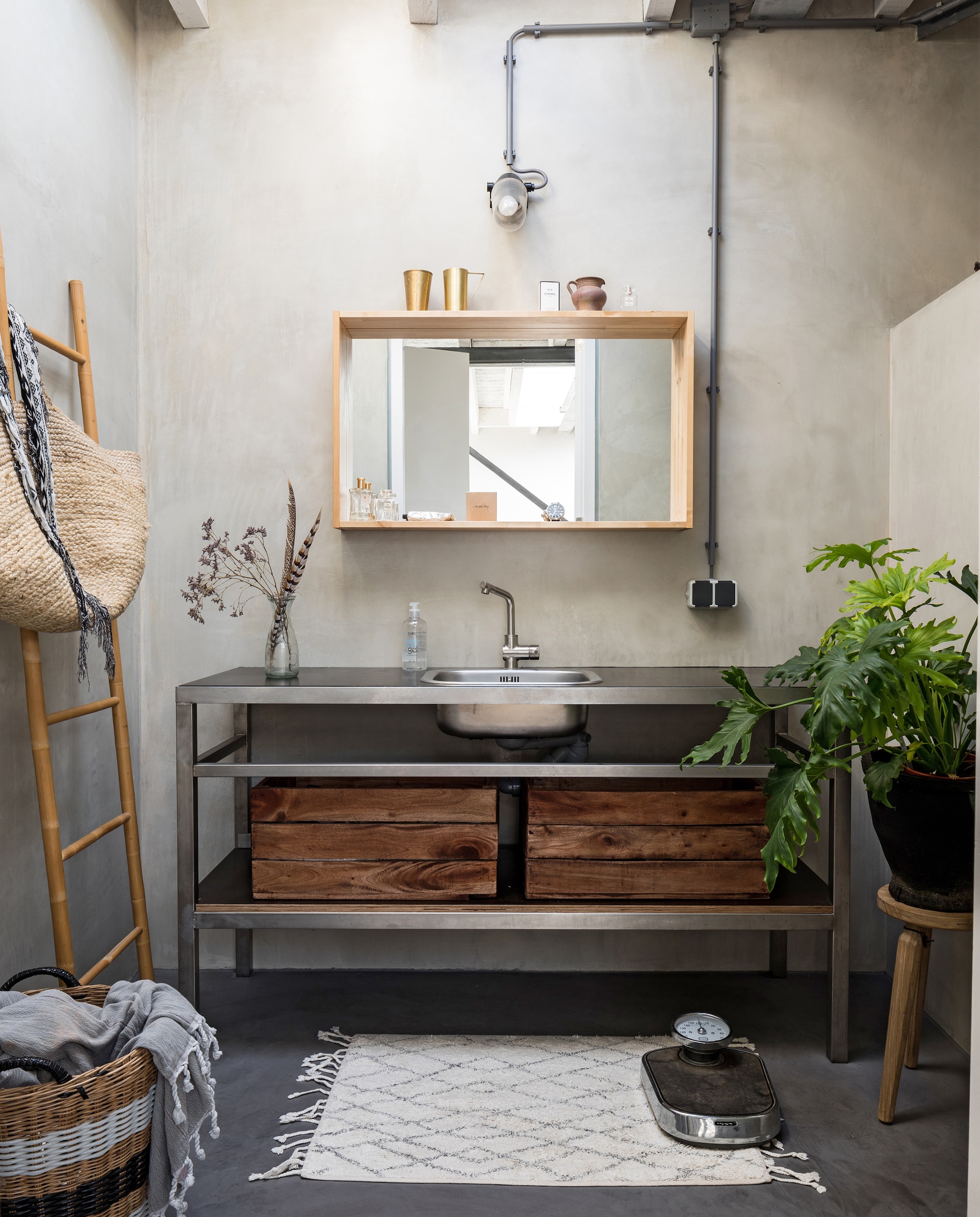 In de badkamer werden alle wanden en de vloer behandeld met beton ciré. De spiegel is van Ikea, het wastafelmeubel is op maat gemaakt van rvs. Houten kistjes van Xenos. Badmat HK Living, weegschaal Dille &amp; Kamille, ladder Hübsch. Oude mand van Mariekes moeder gekregen, hamamdoek en tas van grooothandel Tica. Bron: vtwonen 09-2019 | Styling Sabine Burkunk, Buro Binnenhuis | Fotografie Hans Mossel