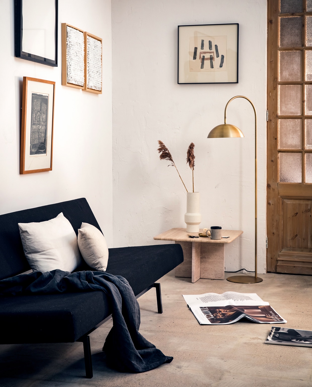 Vloerlamp Jupiter* brons met antiekfinish, 144×47,5 cm (hxb), kap Ø 28 cm, voetplaat Ø 28 cm. Ook in deze serie, allemaal in brons met antiekfinish: tafellamp Jupiter*, 51×28 cm (hxb), kap Ø 20 cm, voetplaat Ø 18 cm, klemlamp Jupiter*, 78×30 cm (hxb), kap Ø 20 cm, wandlamp Jupiter*, 68×50 cm (hxb), kap Ø 20 cm. *met led-verlichting. M.m.v. cocooncollectables.nl (vintage slaapbank, tafel van travertin, lijsten), hkliving.nl (vaas), hm.com (zwart laken, wit groot kussen), bymolle.com (langwerpig linnen kussen), overig privébezit. styling Marlies Does, fotografie Ernie Enkelaar