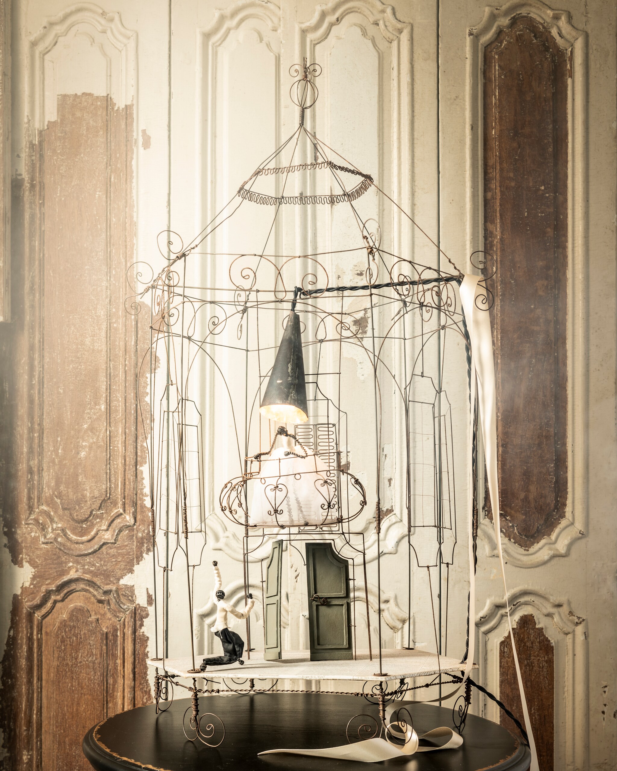 Handgemaakte lamp van ijzerdraad € 995,- (brechtmurreatelier.nl). Houten luiken per stuk € 175,- (burbri.nl). Bijzettafel € 85,- (harlequin-lisse.biz). vtwonen 10-2021 |  styling Liza Wassenaar | fotografie Sjoerd Eickmans | assistentie Kula Isabelle van den Broek | bloemstyling Judith Slagter