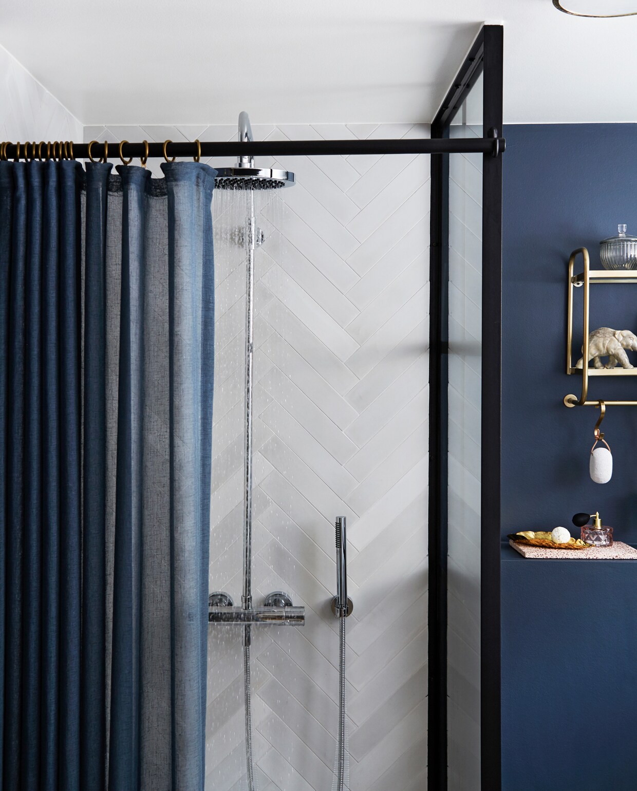 In de badkamer zorgen de Marokkaanse vloertegels, de matte donkerblauwe muren en messing details voor een behaaglijke wellness sfeer. Handgemaakte cementtegels Aztec Milk/Kohl, visgraat wandtegels Stix Fog, beide van Marokk. Het industriële glas is gemaakt door One Funky en Helstrand Smedje. vtwonen nr. 2 2020 | Styling en tekst Rikke Graff Juel | Fotografie Anitta Behrendt/Living Inside | Tekstbewerking Ina Babbé