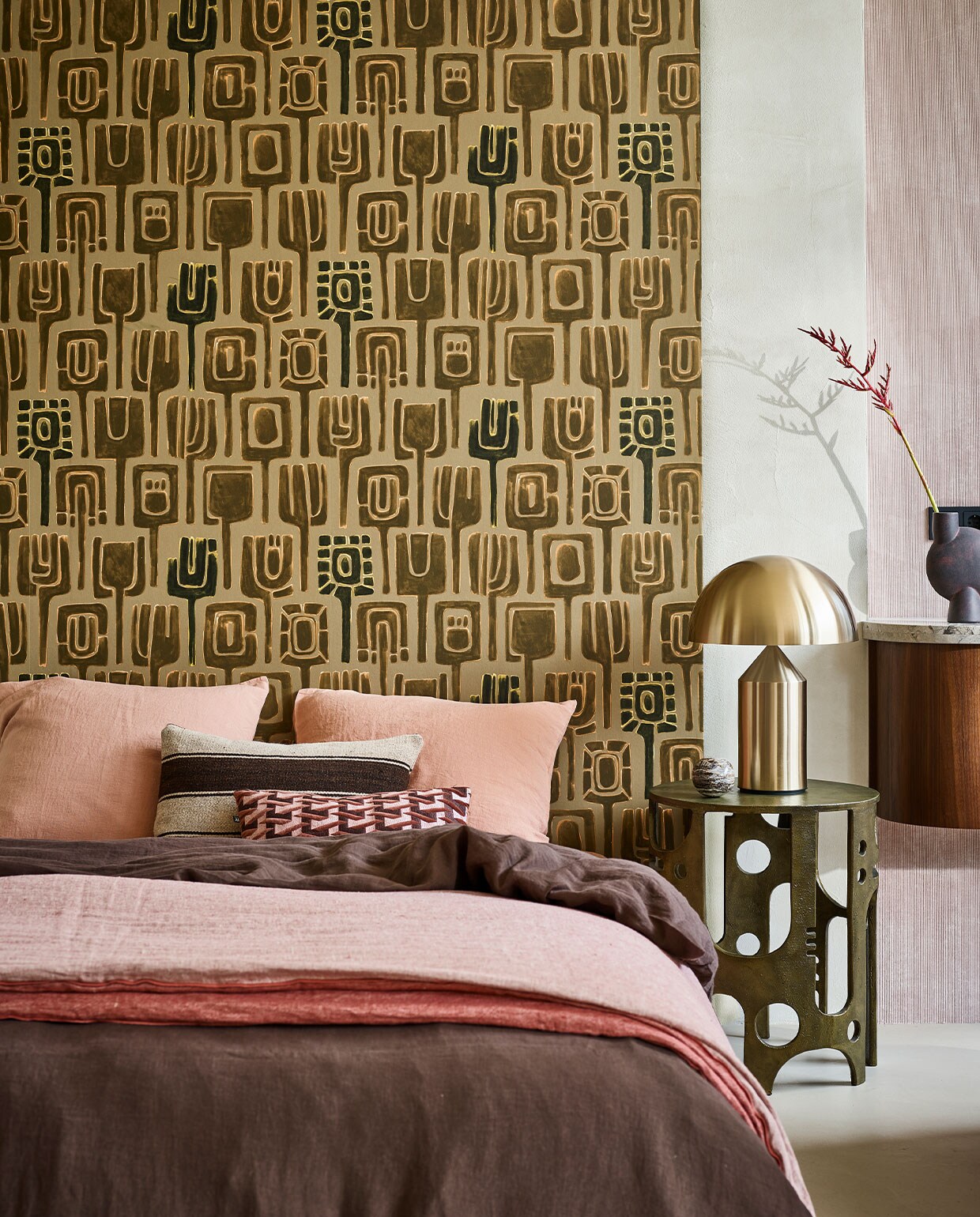 Behang Totem TP31001 van Élitis, 1000×70 cm per rol € 174,- (loggerewilpower.com). Goudkleurige bijzettafel € 887,50 (versmissen.nl). Goudkleurige tafellamp Atollo van Oluce, € 1126,25 (homestede.nl). Bruine ronde vaas Sphere € 40,50 (casagitane.com). Donkerbruin linnen dekbedovertrek, 220×240 cm € 325,-, kussenslopen, 65×65 cm per stuk € 39,-, rozerode deken Cocoon Vice Versa, € 550,-, gestreept kussen, 50×30 cm € 125,- (couleurlocale.eu). Roze/bordeaux kussen, 30×40 cm € 49,95 (hkliving.nl). Beeld: Styling Cleo Scheulderman | Fotografie Jeroen van der Spek | Assistentie Krystel Jane Robinson