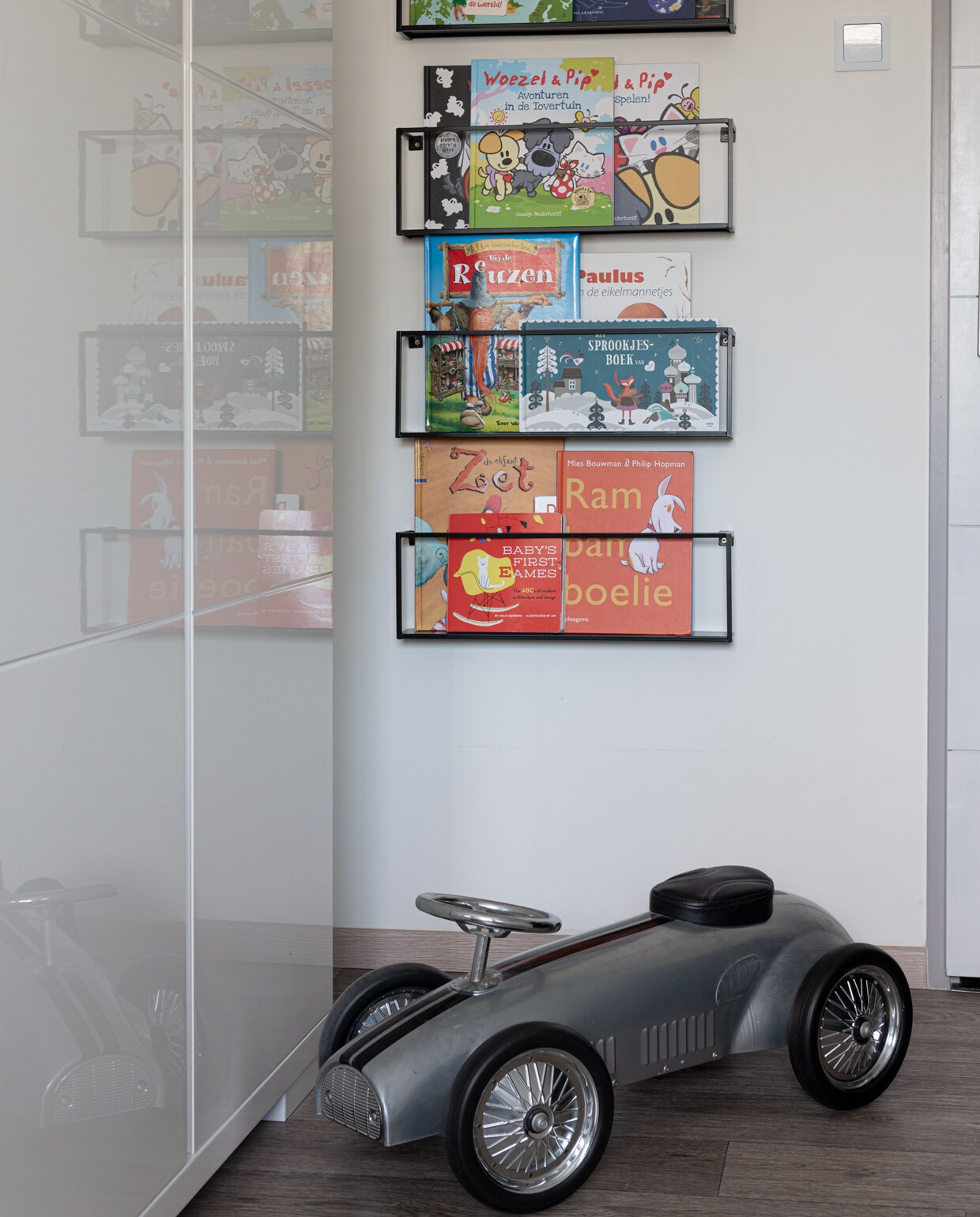 Grijze speelgoedauto en wandrek met kinderboeken vtwonen 09-2021 | styling Sharon Roest | fotografie Caroline Martinot | tekst Sara Madou