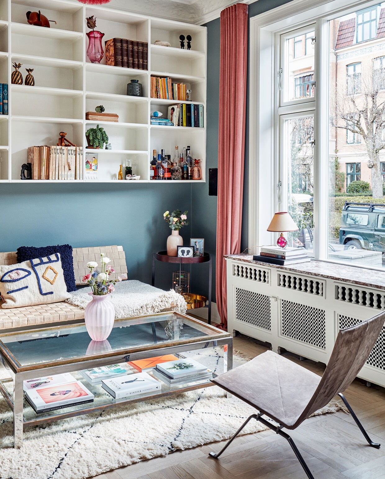 Vergrijsd roze en groen verlevendigen het kleurenpalet in de bibliotheek waar prijzige designklassiekers als de stoel PK 22 van Poul Kjaerholm en een vintage salontafel van Romeo Rega zijn gecombineerd met een daybed van Ikea. Het voorste, handgemaakte kussen is van het Marokkaanse label LRNCE. De boekenkast zat al in het huis.