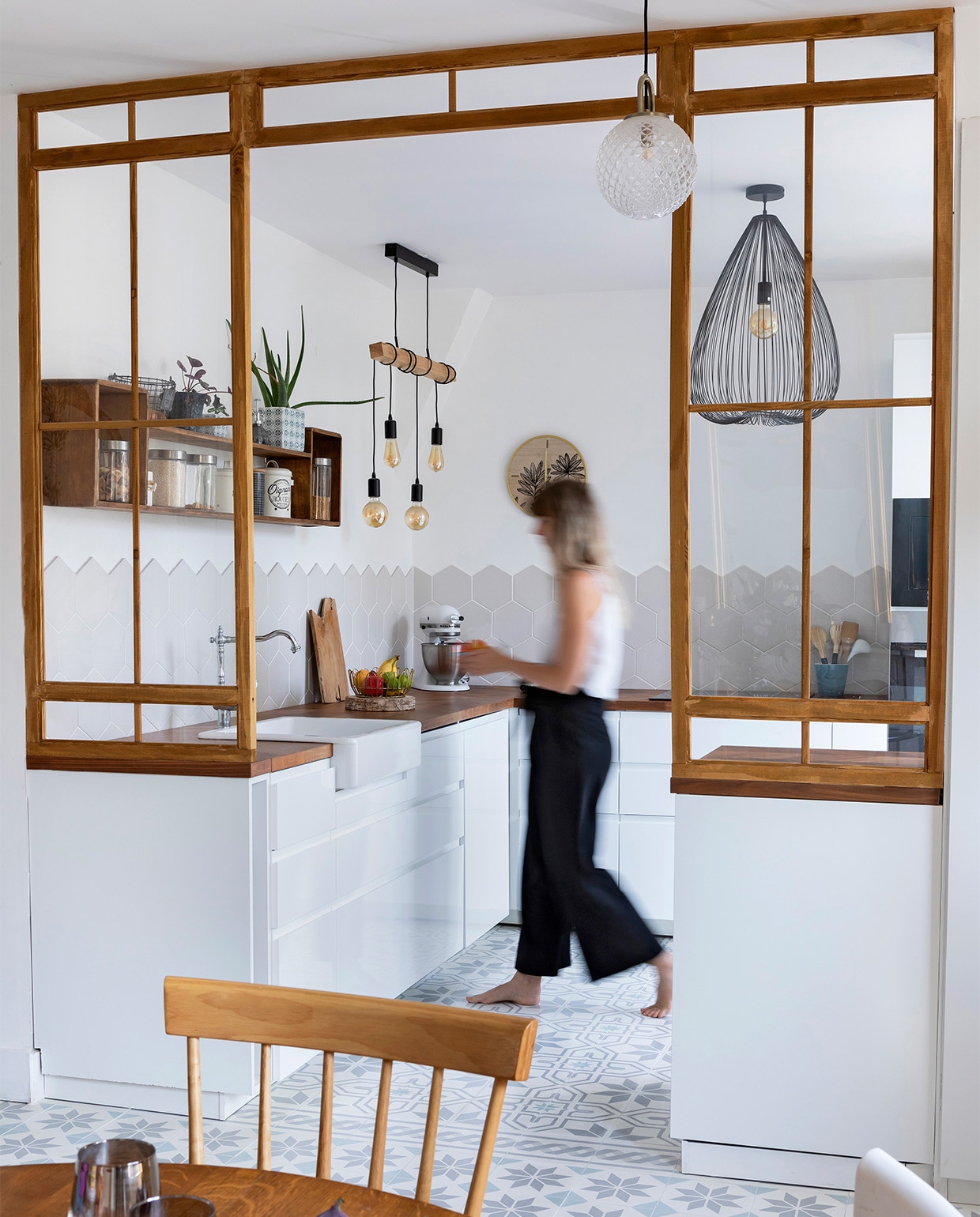 Het rechte aanrecht werd vervangen door een L-vorm en een keukeneiland bij de ingang. Vloertegels Mosaic del Sur. Wandtegels asdecarreaux.com. Keuken Ikea. Houten wandkast tweedehands. Peertjes aan houten balk Leroy Merlin. Zwarte plafondlamp Alinea. Overig onbekend. vtwonen special zomerhuizen 07-2021 | Productie en tekst Anne-Catherine Scoffoni | Fotografie Pauline Legoff