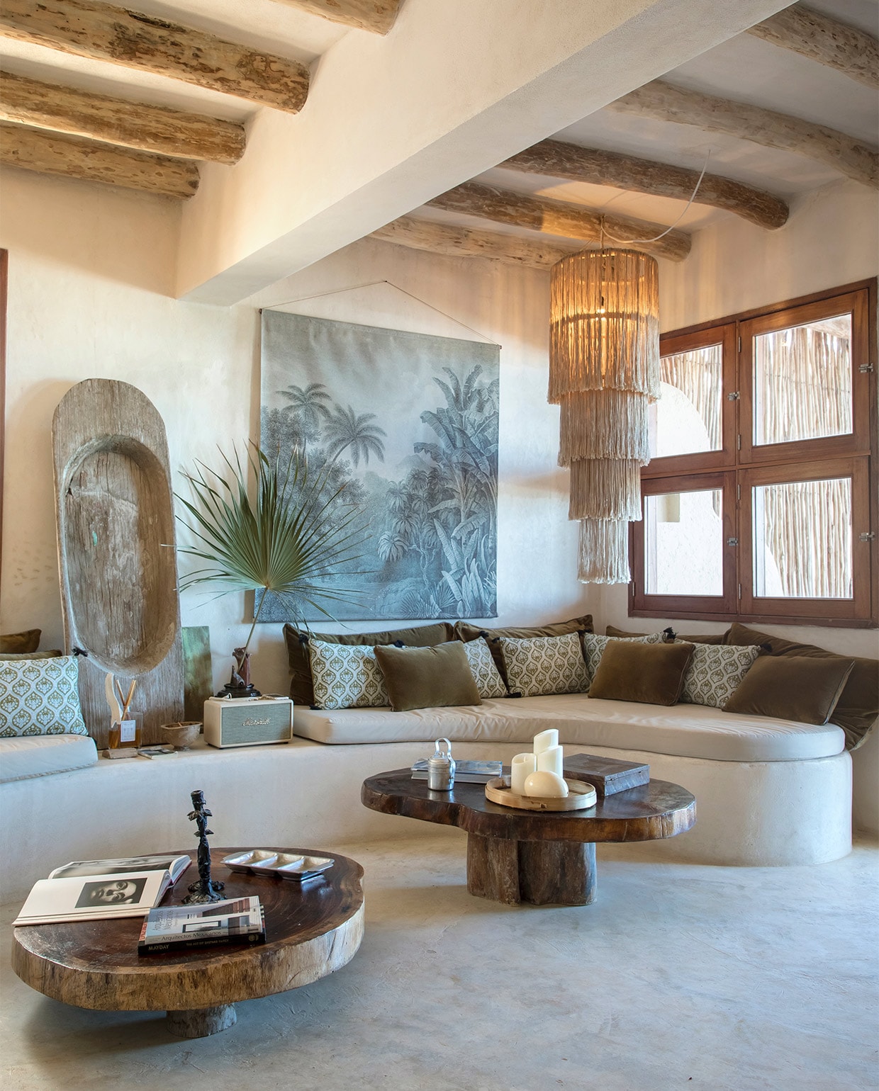 De golvende bank is gemaakt van cement met een coating van fijn zand. Kroonluchter en salontafels lokaal gekocht. Kussens Harmony Textile. Muurdecoratie Jungle van La Maison Pernois vtwonen special zomerhuizen 07-2021 | productie Anne-Catherine Scoffoni | fotografie Cécile Perrinet-Lhermitte