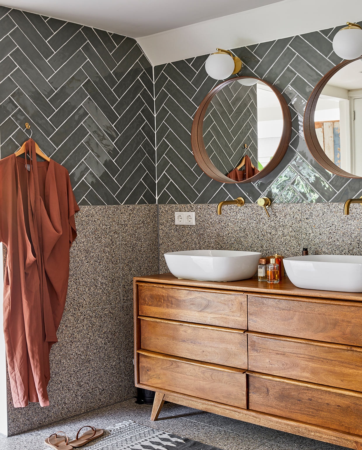 Tegels House of Ceramics. Vloer en muur onder de tegels Patroonfabriek. Spiegels Ikea, lampen Nordlux, kranen One-collection, waskommen Sanitairkamer. Houten ladekast Maisons du Monde. Vloerkleed Kwantum. Jurk herkomst onbekend, slippers Havaianas.