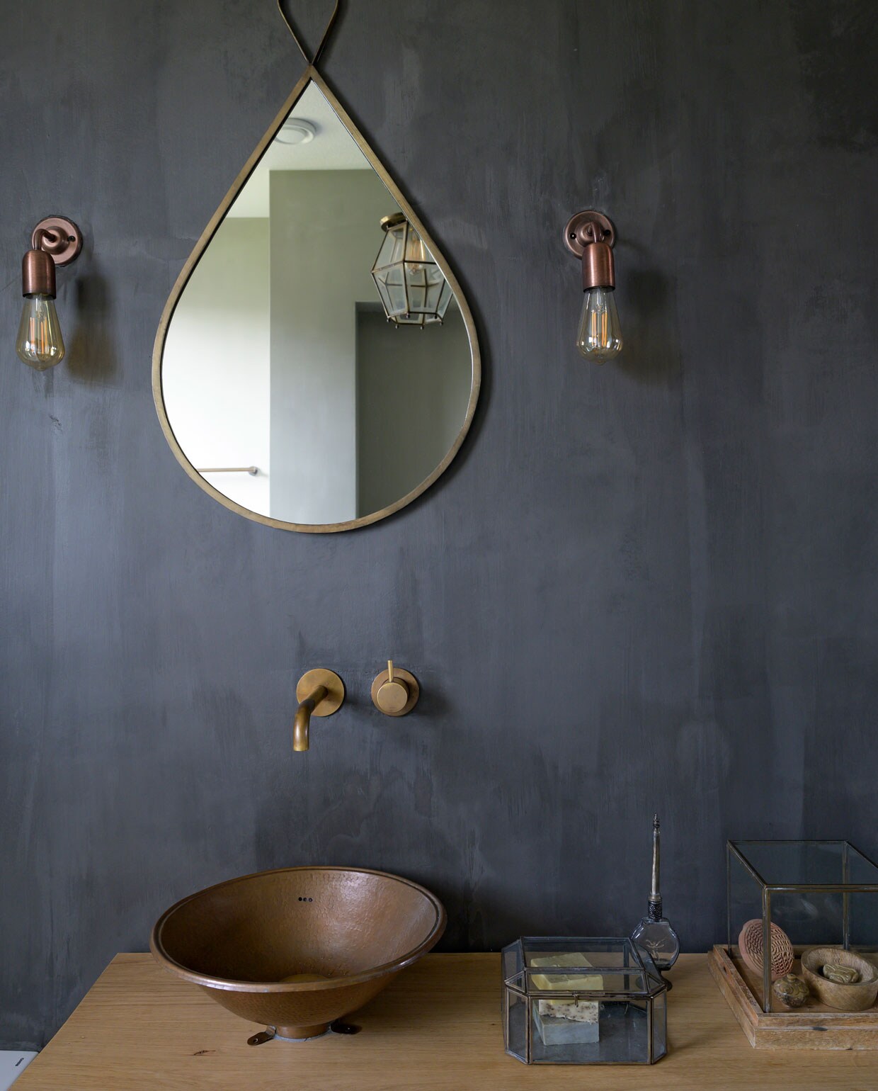 Badkamerwand kleur Graphite met zeer matte vernis Carte Colori. Spiegel Casa Vivante. Wandlampen Etsy. Wastafel op maat gemaakt door een meubelmaker. Kraan in aged brass Hotbath. Wasbekken Sahara Shop. Vitrines Casa Vivante. vtwonen 08-2021 | styling José Spaans | fotografie Stephanie Driessen