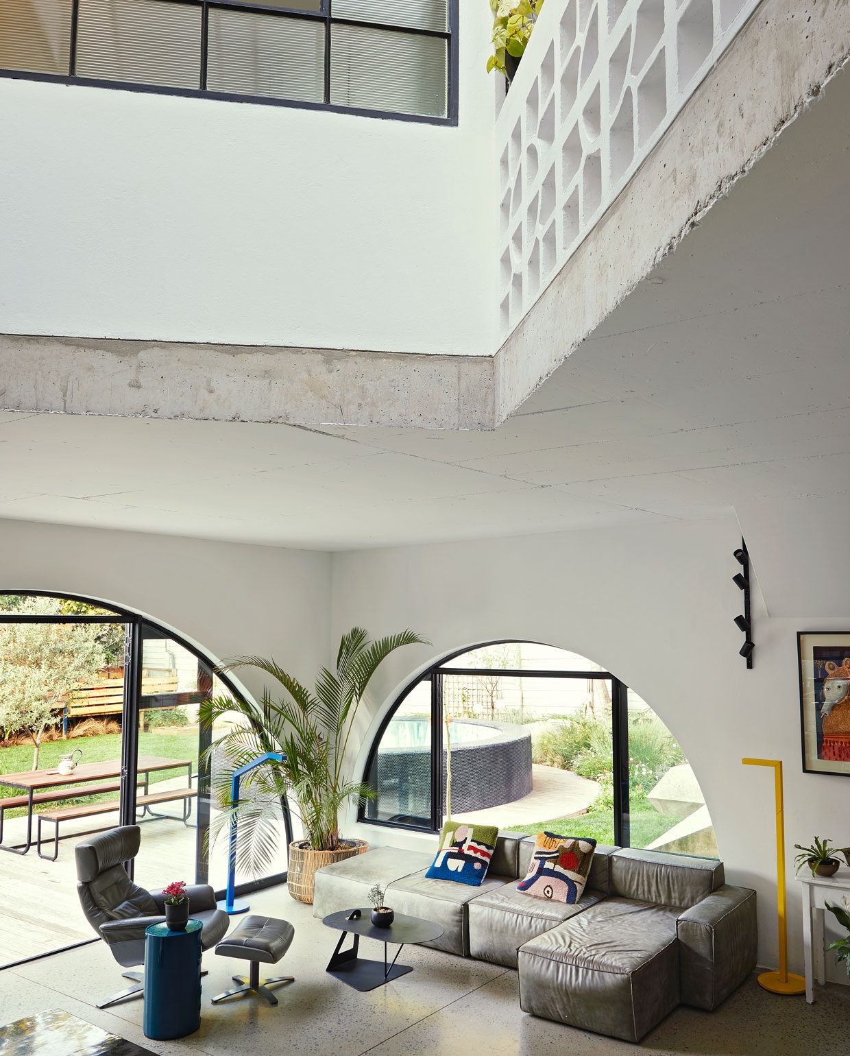 Vloer gepolijst beton World of Decorative Concrete. Bank Weylandts. Kussens Renée Rossouw. Blauwe bijzettafel Componibili Kartell. Rieten plantenbak Amatuli Artefacts. Blauwe en gele lampen Nick-Knack Lirio by Philips. Zwarte wandlamp Spazio. De witte sidetable is een antiek slagersblok met marmeren blad Marmernova. Overig onbeken vtwonen special binnenkijken 06-2021 | productie Living Inside, Bureaux | fotografie Elsa Young