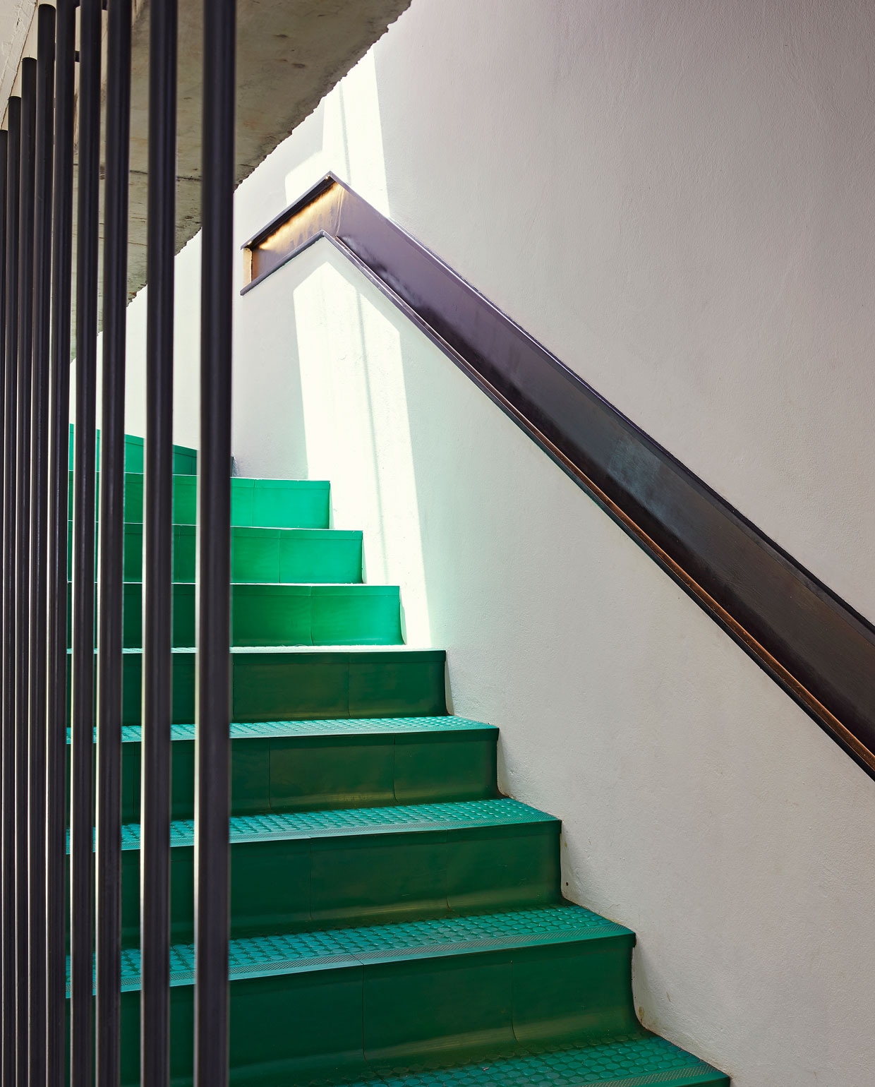Trap gemaakt van in elkaar grijpende PVC-vloertegels in de kleur Summer Green. Verzonken stalen leuning zelfgemaakt. vtwonen special binnenkijken 06-2021 | productie Living Inside, Bureaux | fotografie Elsa Young