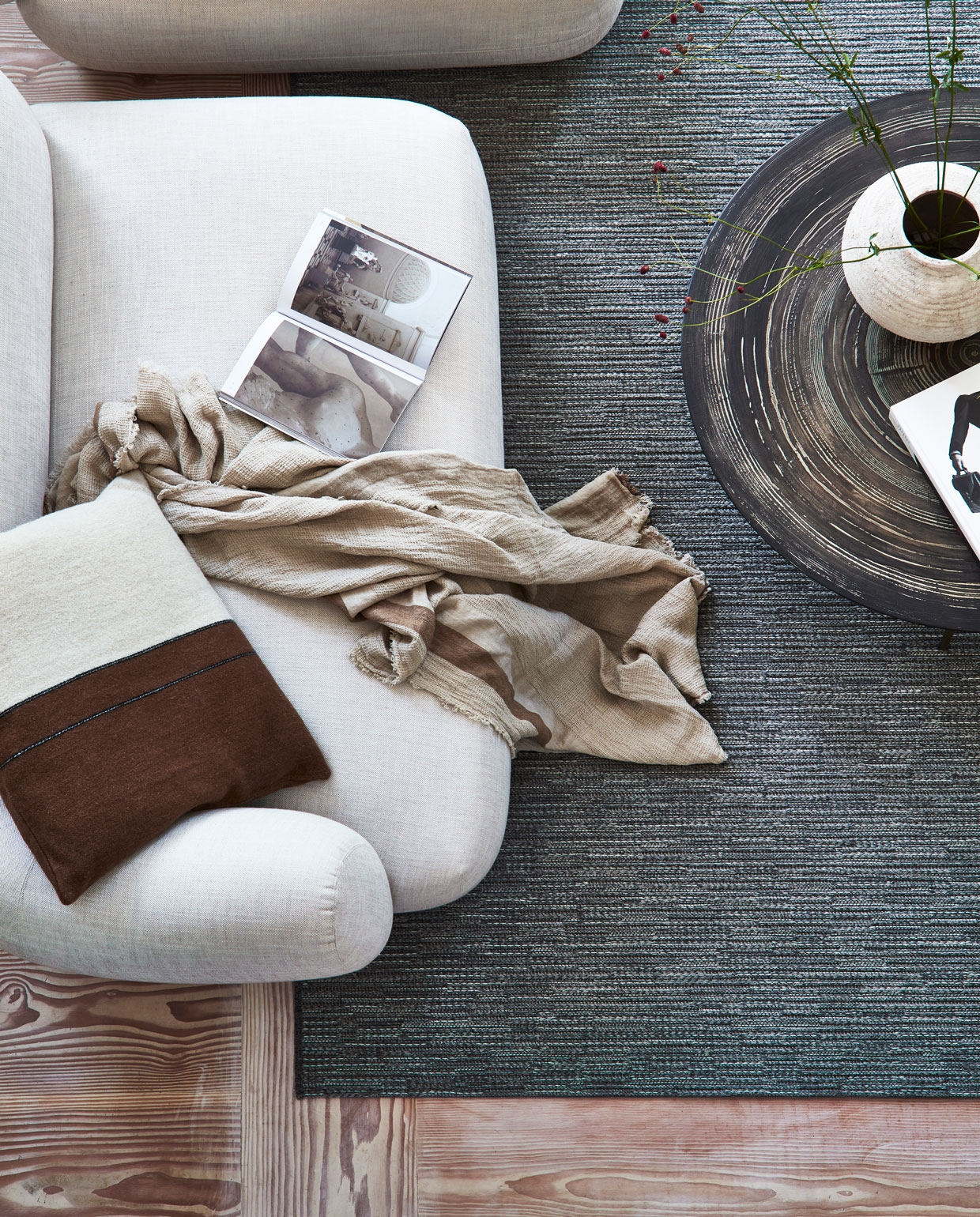 Wollen karpet Nature cord antraciet melé. M.m.v. letoile.store (bruin-wit kussen, plaid), homestede.nl (salontafel), zarahome.com (keramieken vaas op bruine salontafel, stenen vaas op bank met gevlochten zitting, houten opbergbox, slippers), homestede.nl (houten bank met gevlochten zitting), vantil.nl (voetenbank), sissy-boy.com (kom). Overig privébezit. Productie Tanja Saarberg | styling Danielle Verheul | fotografie Sigurd Kranendonk | assistentie sanne ketelaar
