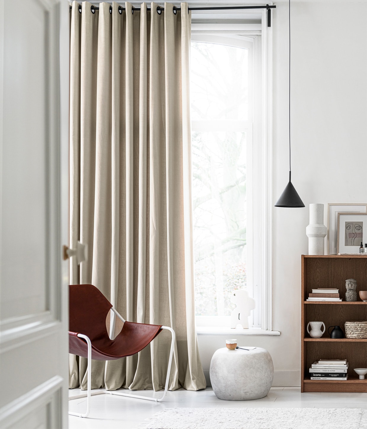 Gordijn op maat in stof Cosy kleur 1166, per meter € 31,99. M.m.v. extravert.nl (stoel met leer van Paulistano), basiclabel.nl (bijzettafel Pebble), hkliving.nl (hanglamp, vaas, object in vensterbank, mok op voet), loods5.nl (mok, vaas in kast, mand, grijs object, terra kom), wonderwallstudios.com (ingelijst kunstwerk). Overig privébezit.