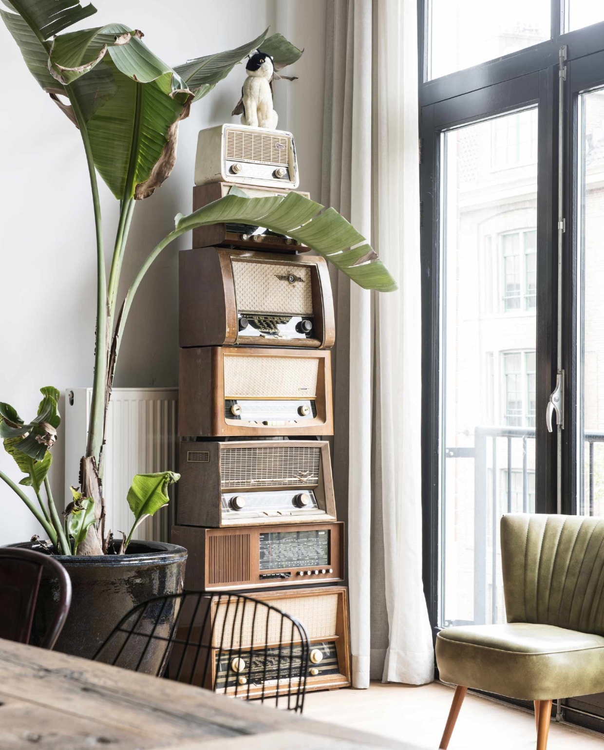 Marmeren eettafel via Marktplaats, stoelen Voga. Rotan kandelaar The Knot of Friendship van de Oostenrijks/Zweedse architect Josef Frank was een huwelijkscadeau van Zweedse vrienden. Vaas en bruin kopje H&amp;M, bruin bakje Kwantum, plantenstandaard en bloempot Praxis, kast Ikea. Het kunstwerk aan de muur is een door Annet bewerkte foto. beeld: vtwonen 11-2017 | Fotografie Fotolemaire.nl | Styling Kim Timmerman