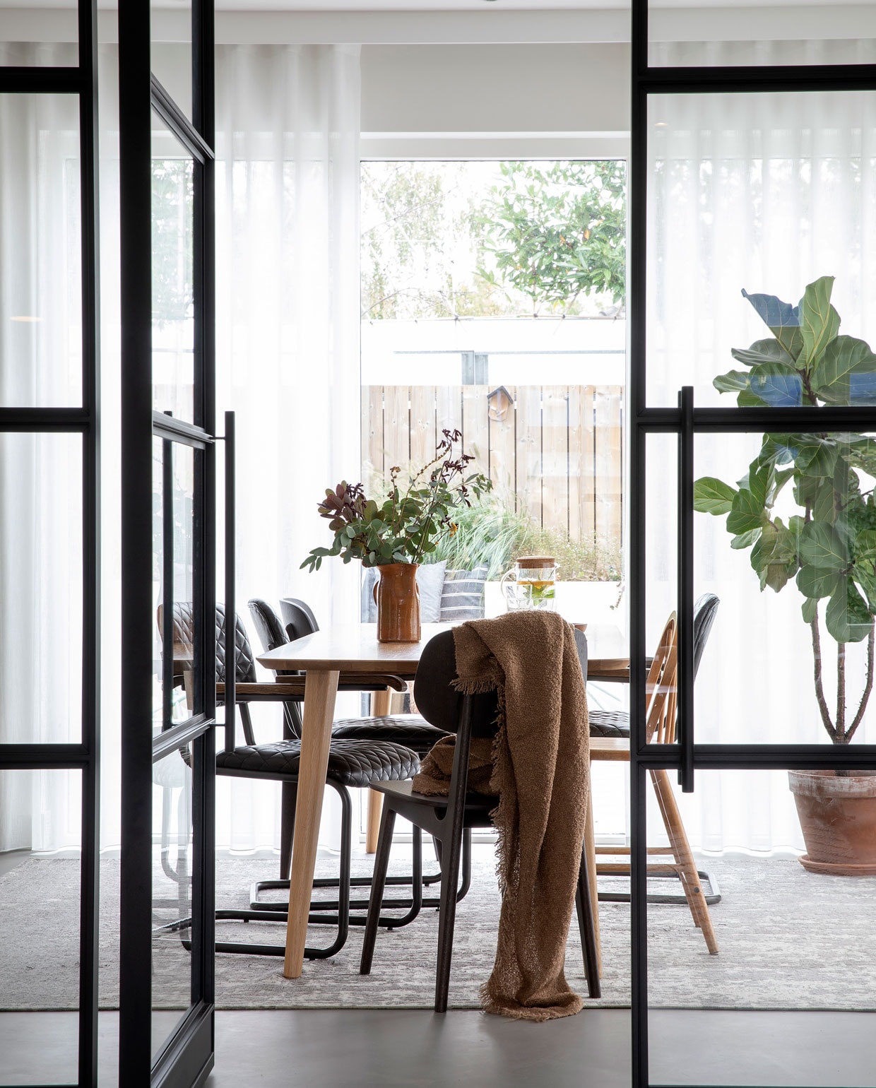 Deuren met stalen kozijn op maat gemaakt door Wout Jansen. Tafel Sav &amp; Økse. Stoelen By-Hoo. Hoge kinderstoel Ikea via Marktplaats. Vloerkleed Floorpassion. Plaid H&amp;M Home. Vaas van de kringloopwinkel. fotografie Mascha Gutlich